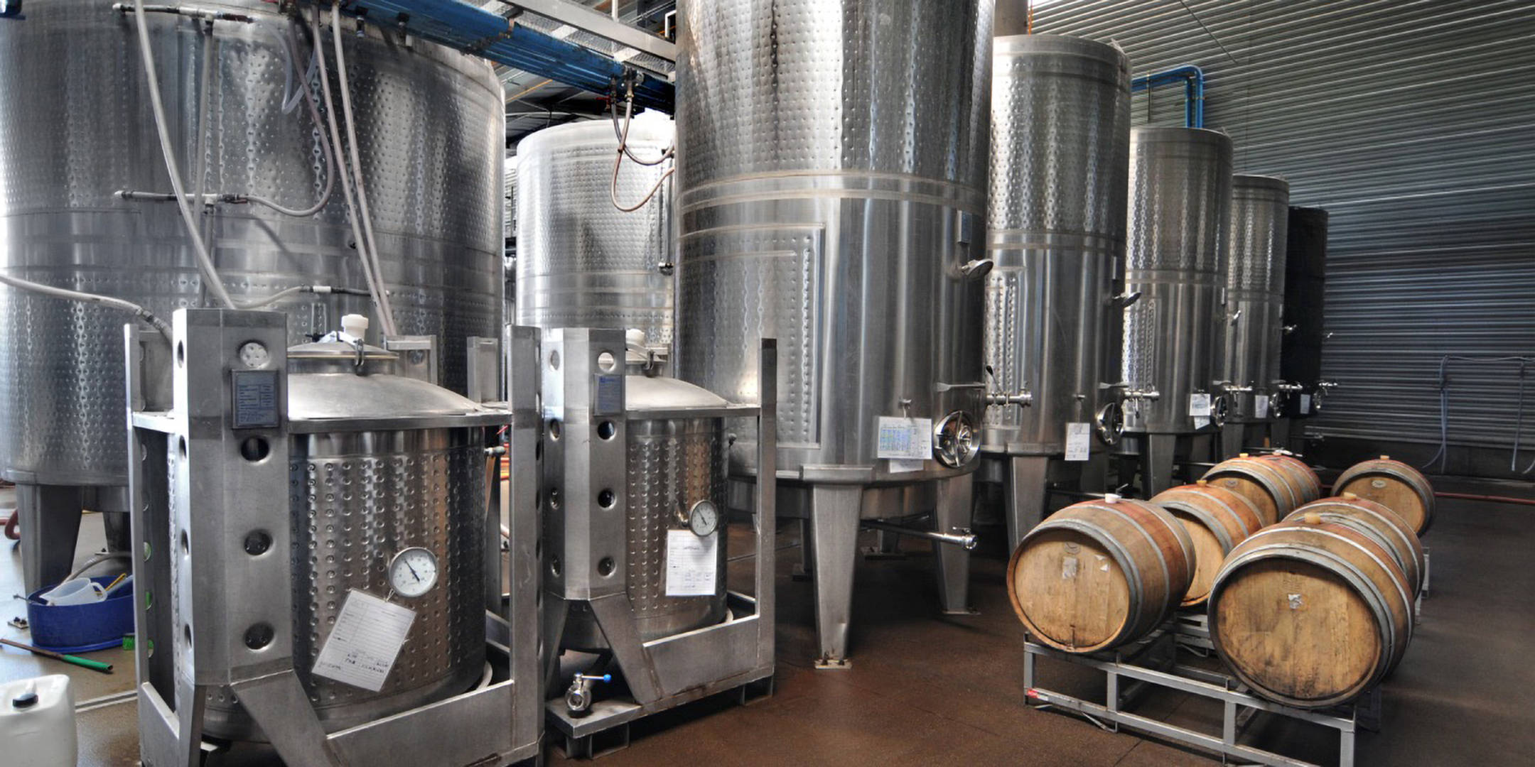 Gärbehälter aus Edelstahl und Holzfässer.