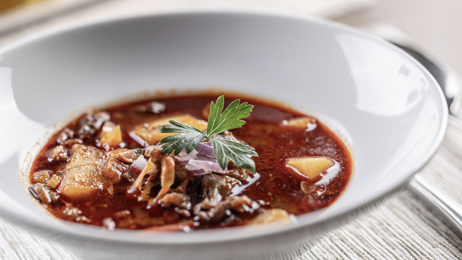 Teller mit Eintopf, Kartoffeln und Petersilie.