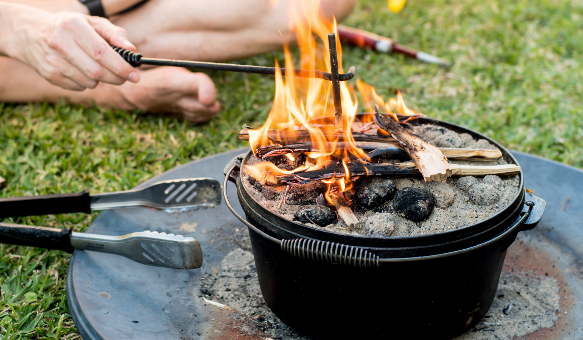 Dutch Oven mit Asche, Kohle und brennendem Holz.