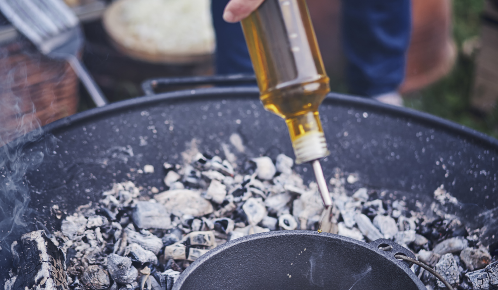 Öl wird in Dutch Oven an der Feuerstelle zum Anbraten geschüttet.