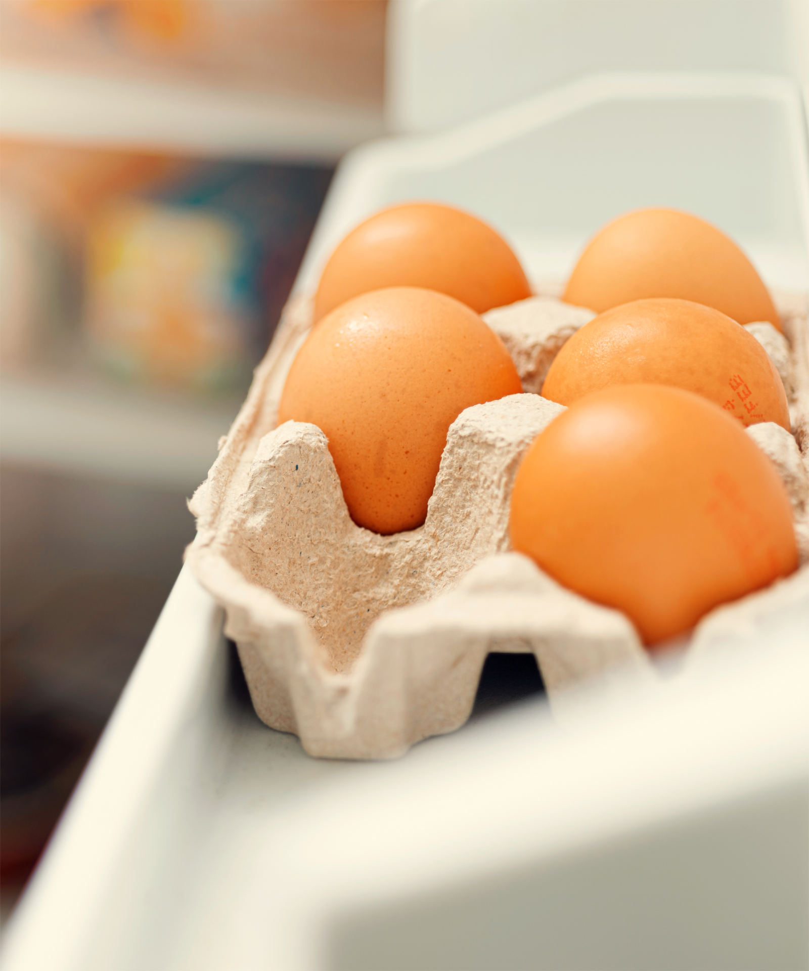 Ein Eierkarton gefüllt mit Eiern im offenen Kühlschrank.