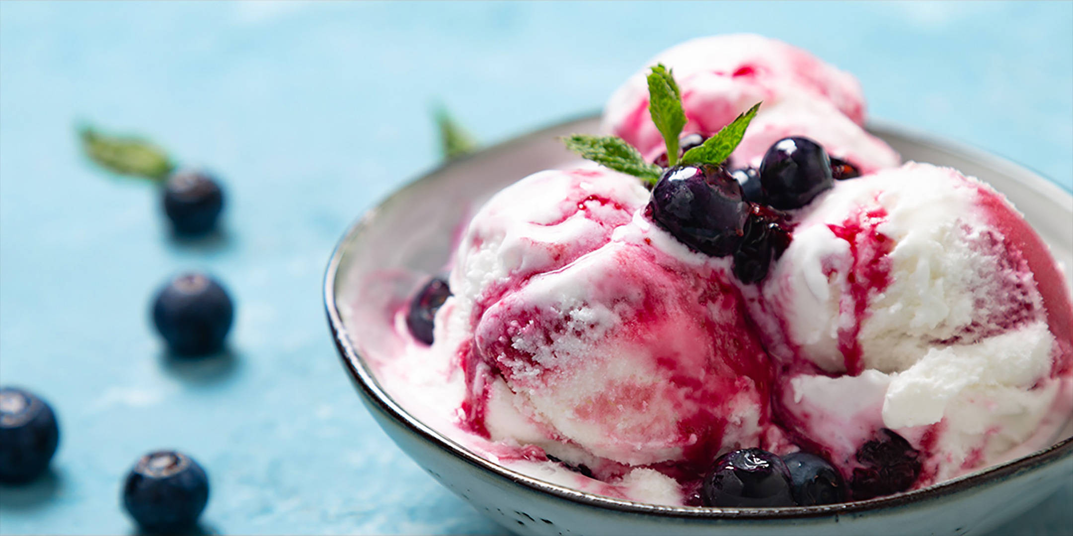 Vanilleeis mit Heidelbeeren, Beerensauce und Minze in Schale.