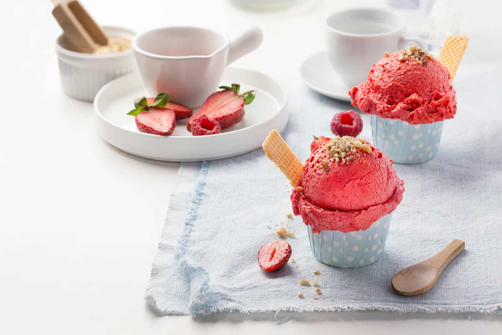 Zwei Erdbeersorbets angerichtet wie Cupcakes auf einem gedeckten Tisch.