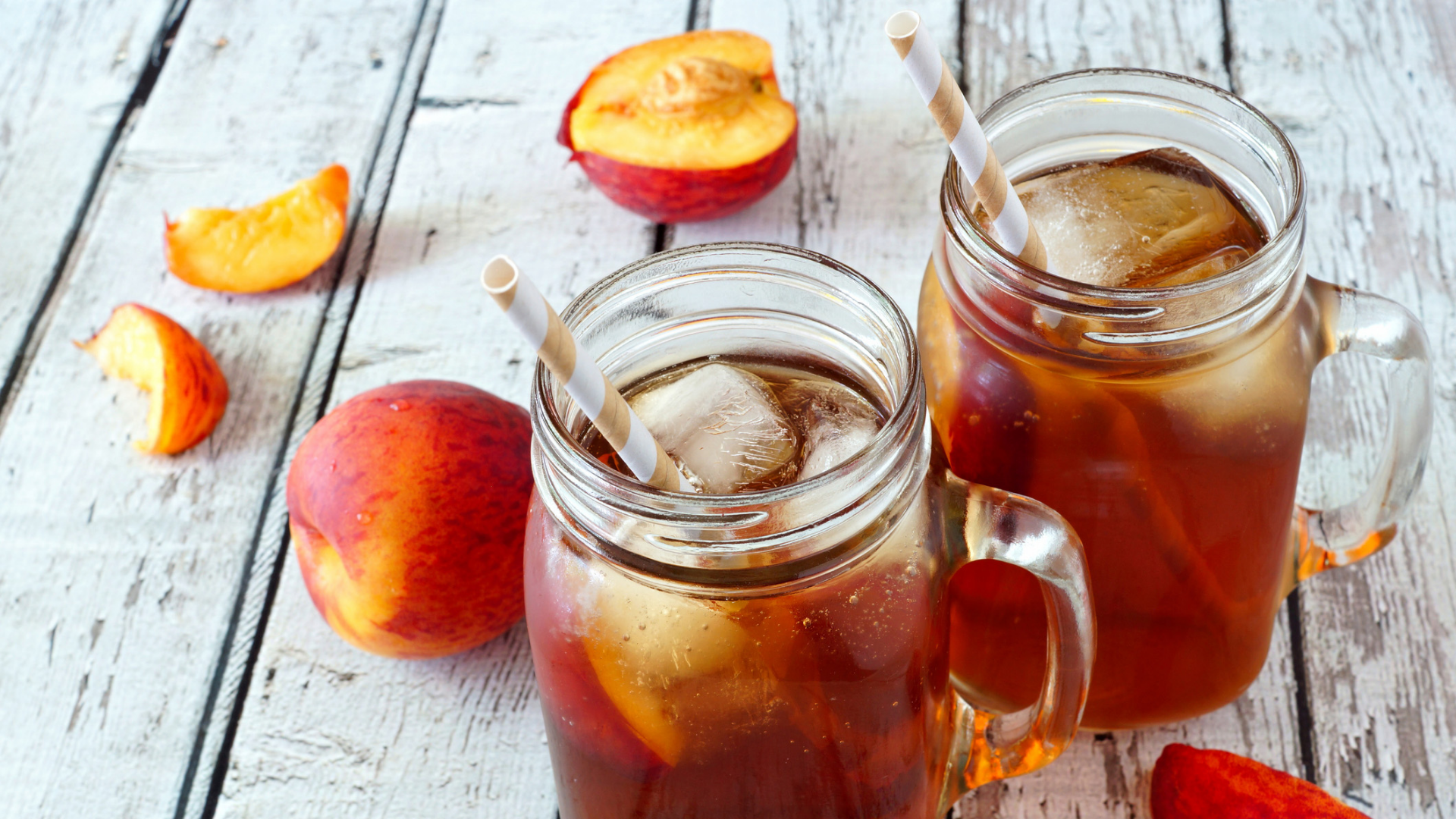 Pfirsich-Eistee in Gläsern mit Eis und Strohhalmen.