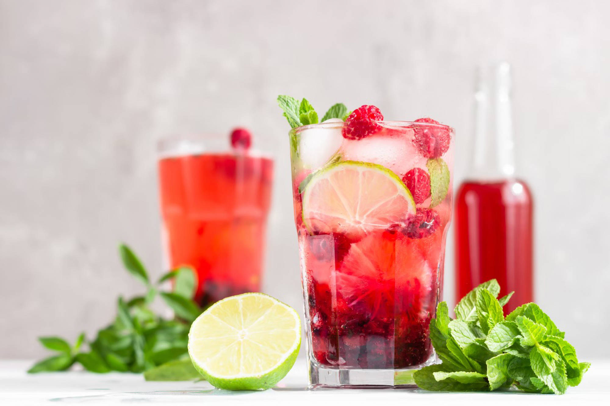 Ein Glas mit rotem Eistee, mit Limetten und Minze. 