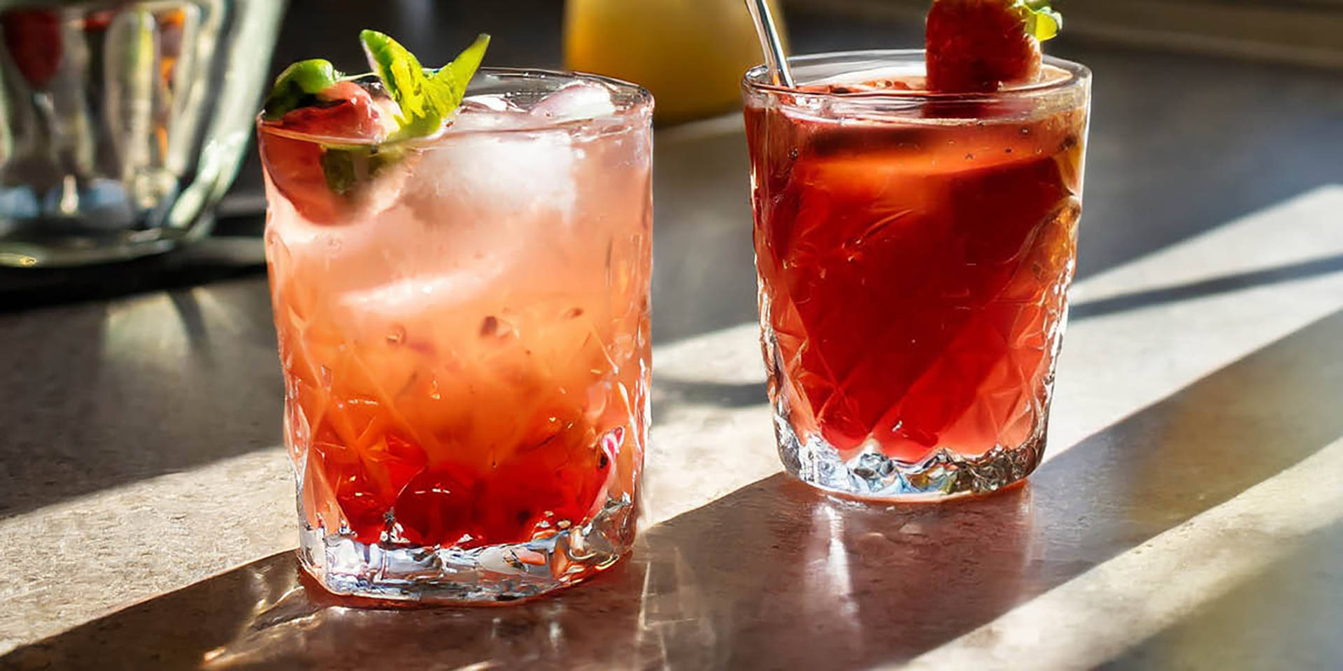 Zwei erfrischende Erdbeergetränke mit Eis und Früchten.