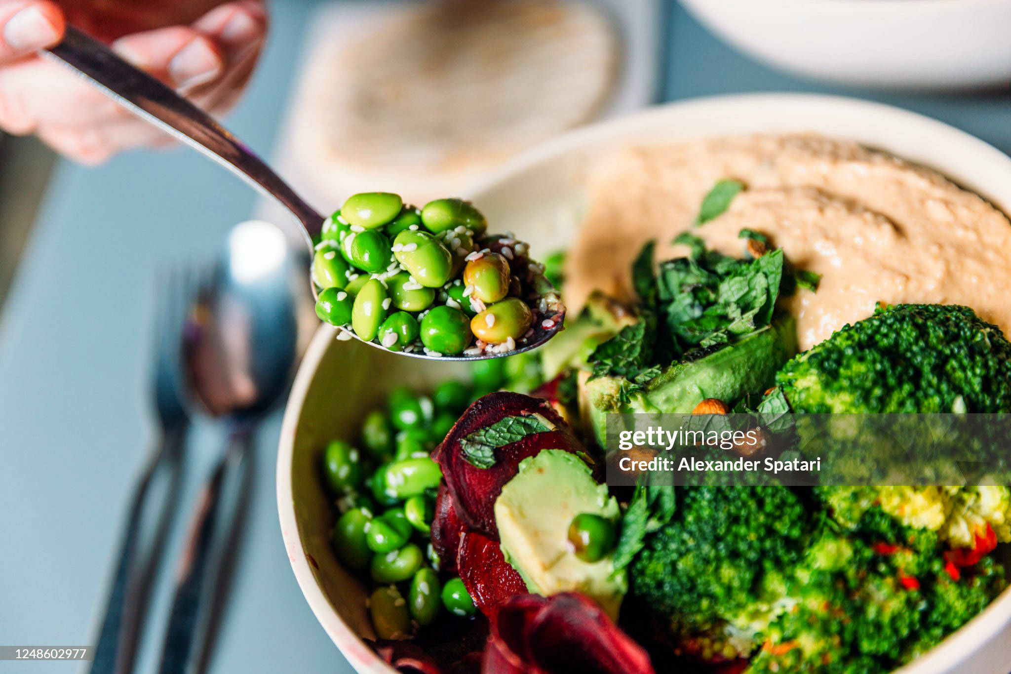 Vegane Bowl mit Edamame Bohnen, Broccoli, Avocado, Rote Beete, Hummus und Nüssen.