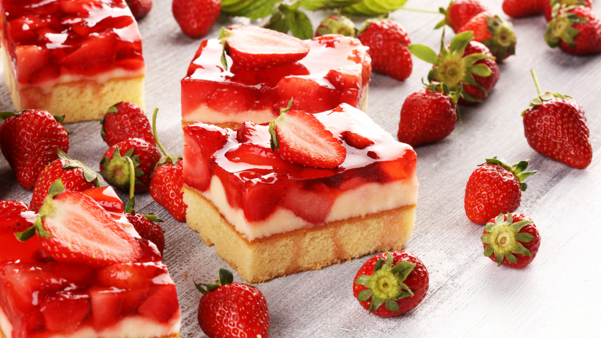 Mehrere Erdbeerkuchenstücke mit Erdbeeren und rotem Gelee.