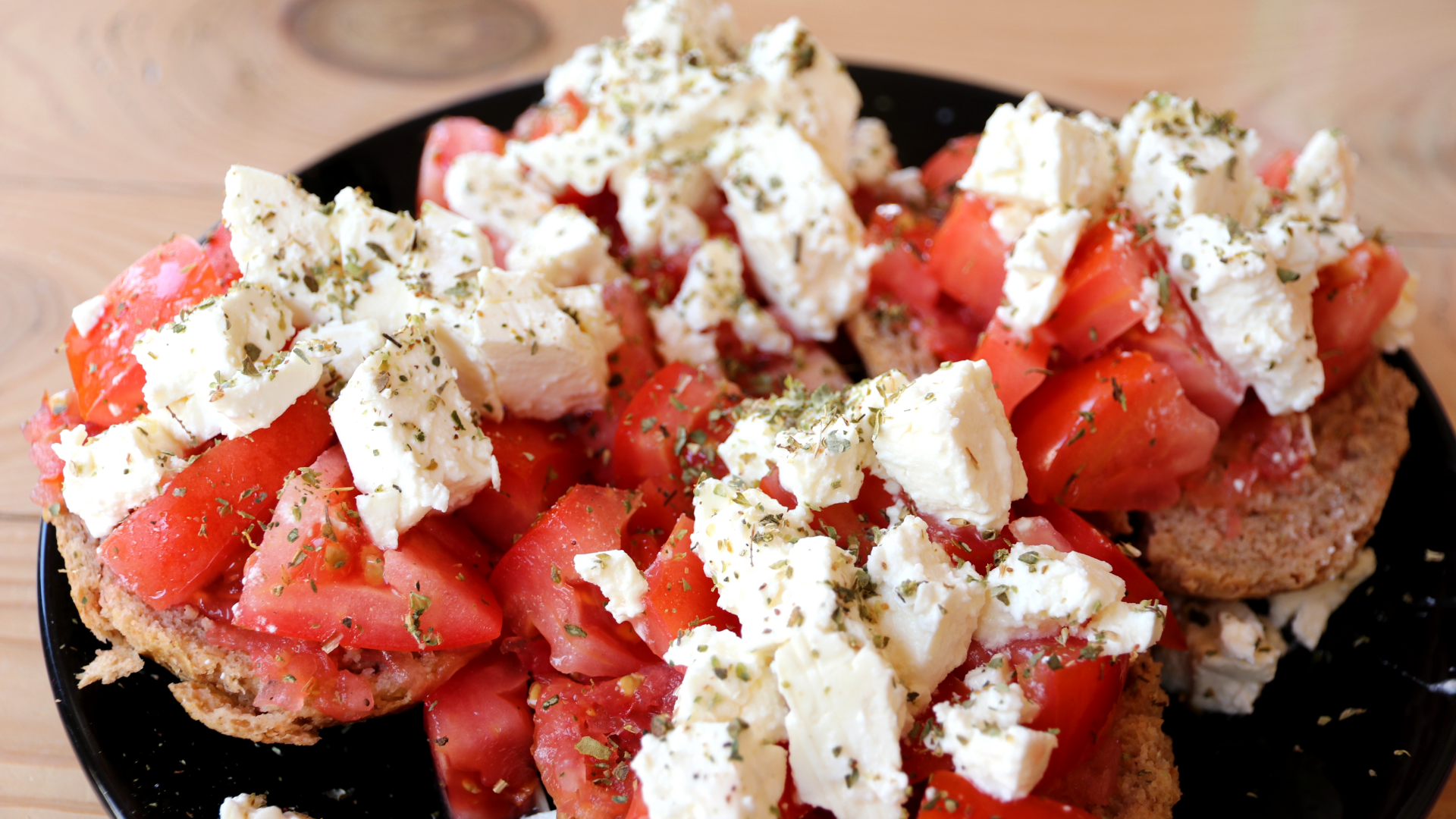 Brot mit Tomaten, Feta und Kräutern auf Teller.