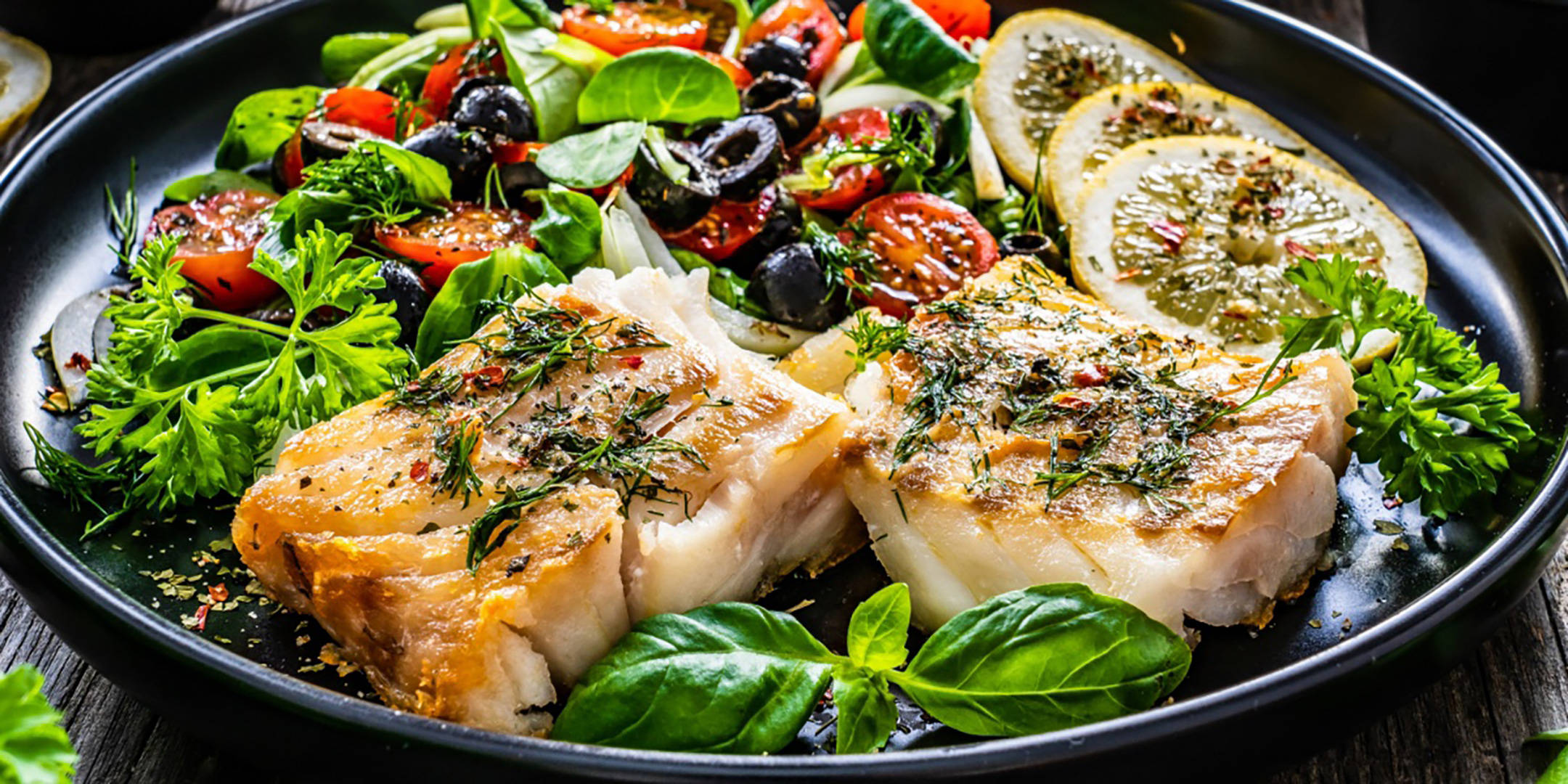 Gebratenes Fischfilet mit Kräutern, Zitrone und Gemüsesalat.