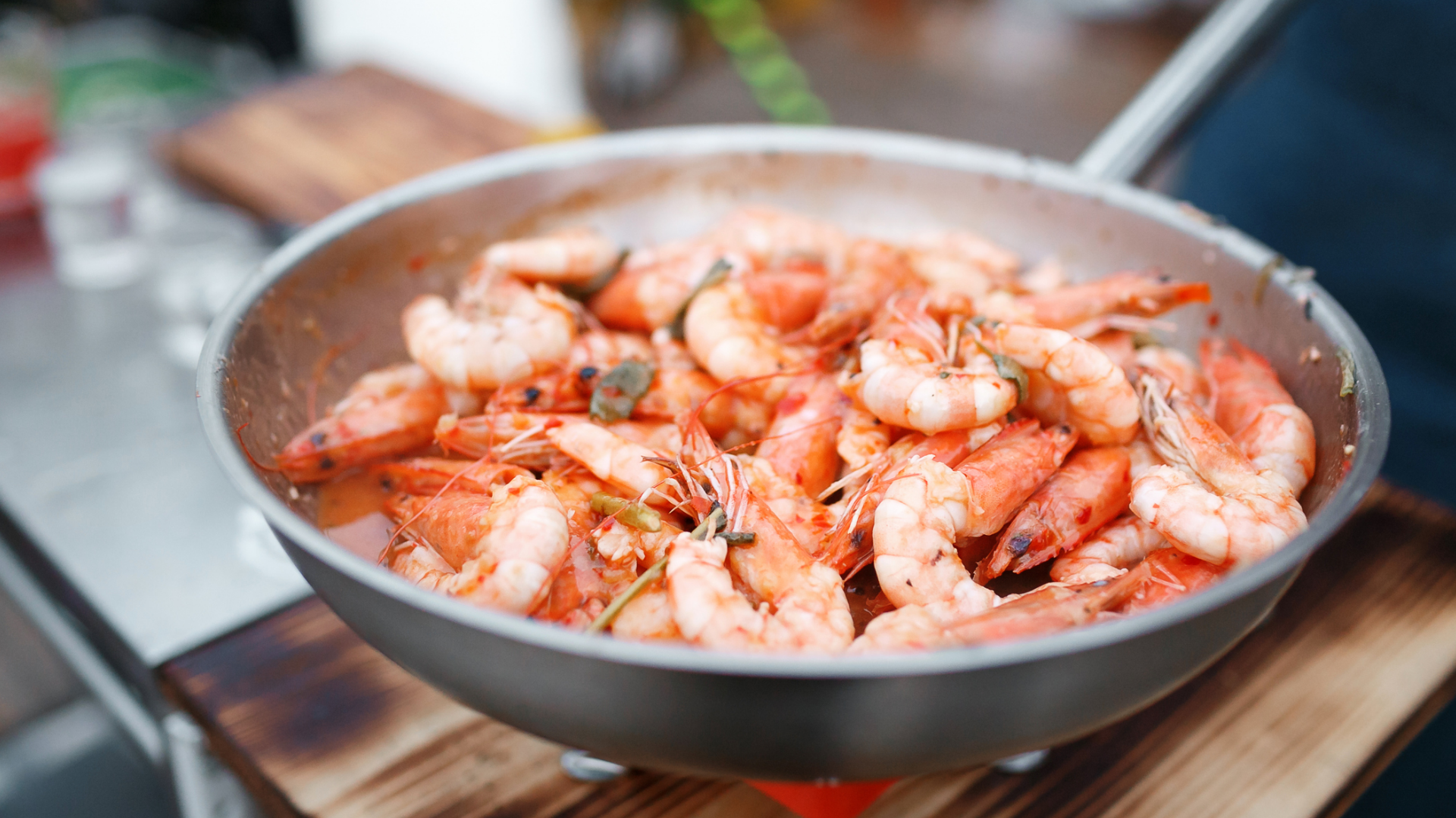 Gegarte Garnelen mit Kräutern in Pfanne.