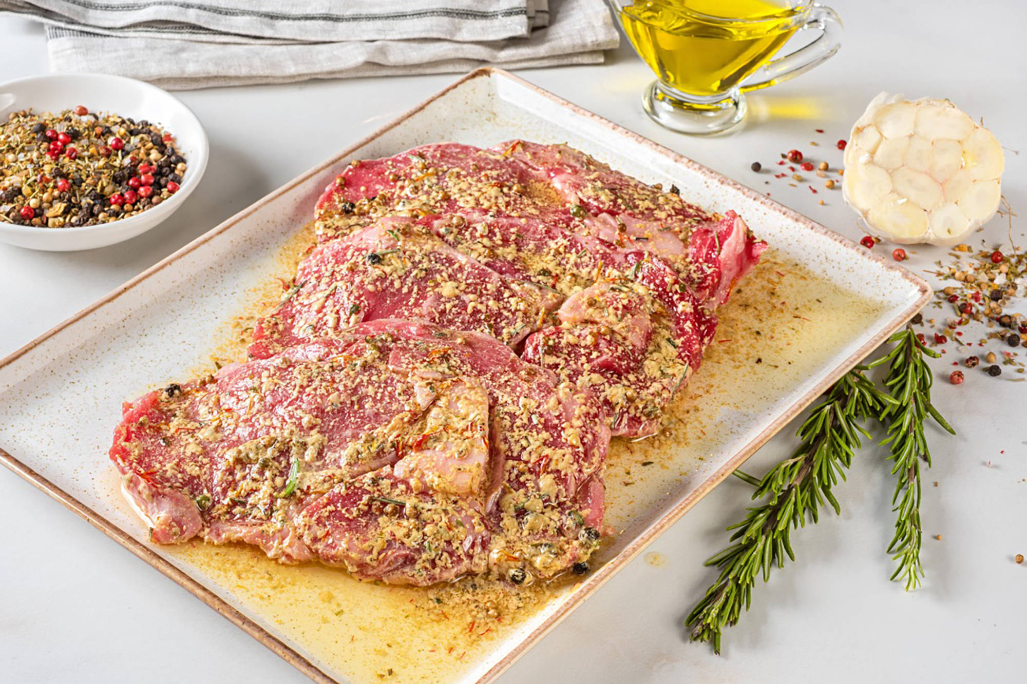 Mariniertes Fleisch mit verschiedenen Kräutern in einer Form.