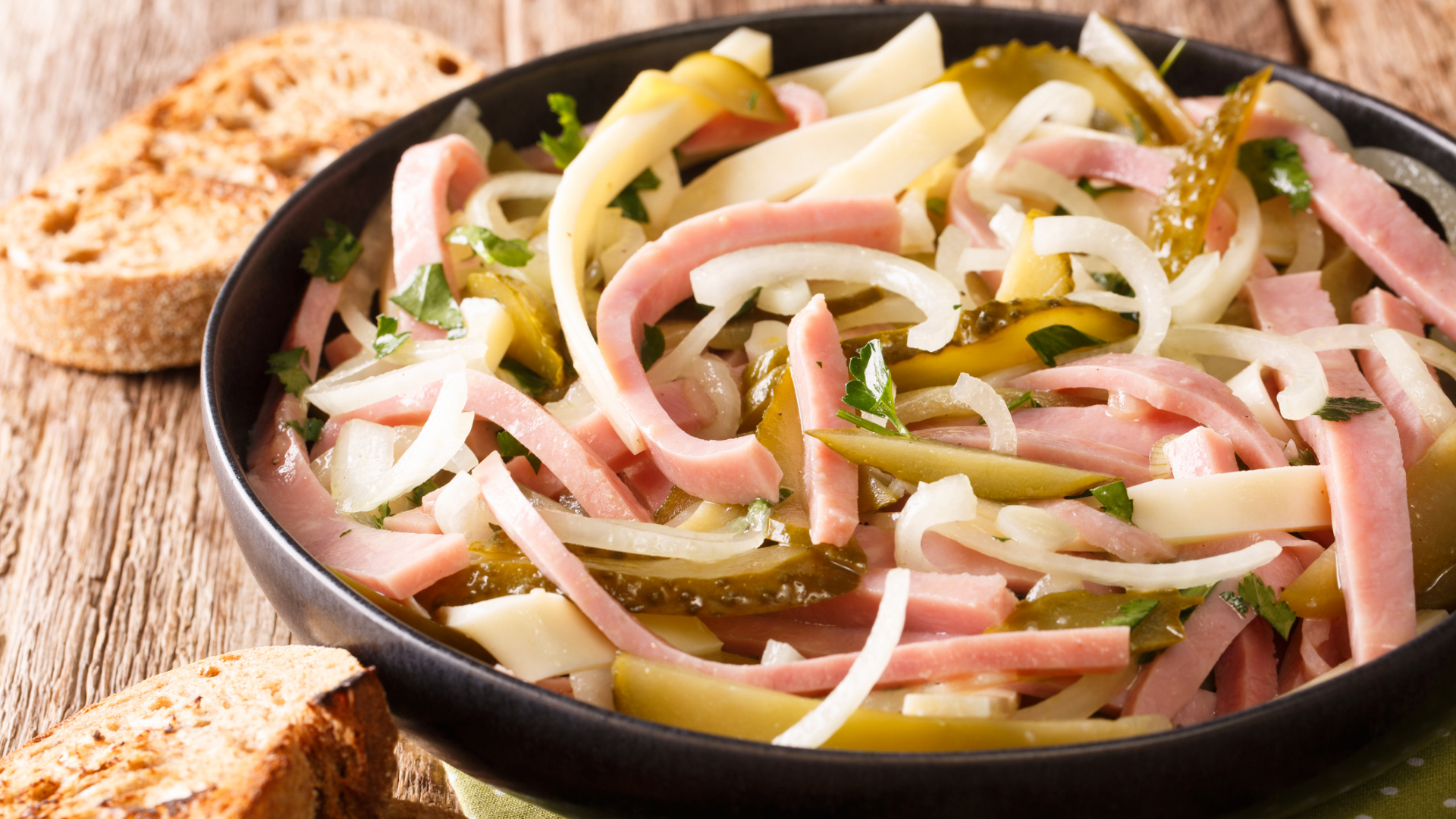 Wurstsalat mit Zwiebeln, Gurken, Käse und Brot.