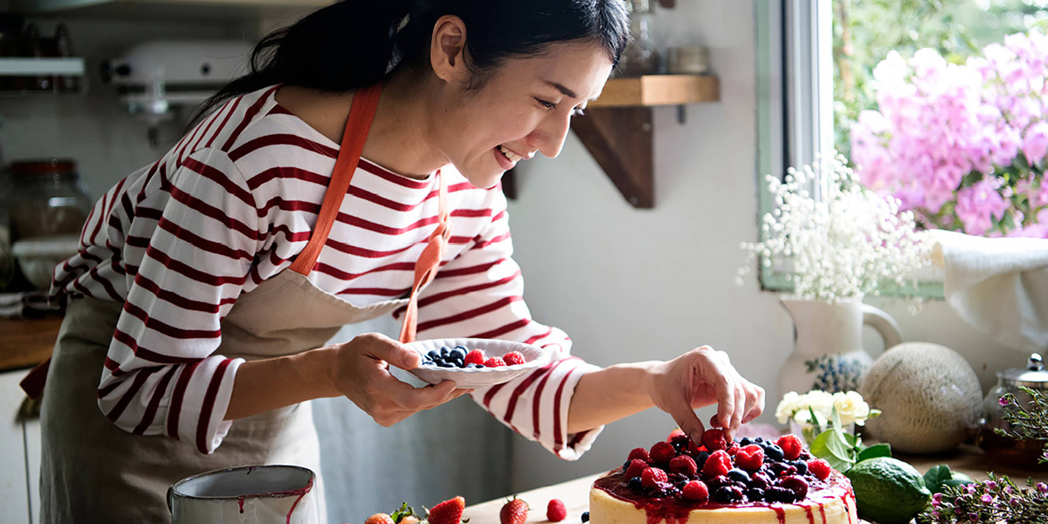 Frau dekoriert Käsekuchen mit frischen Beeren.