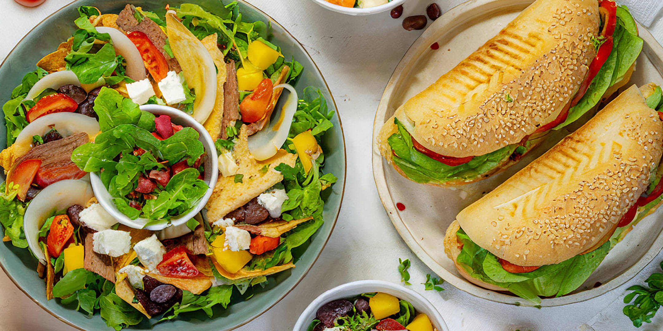 Verschiedene Salate und Sandwiches auf dem Tisch.