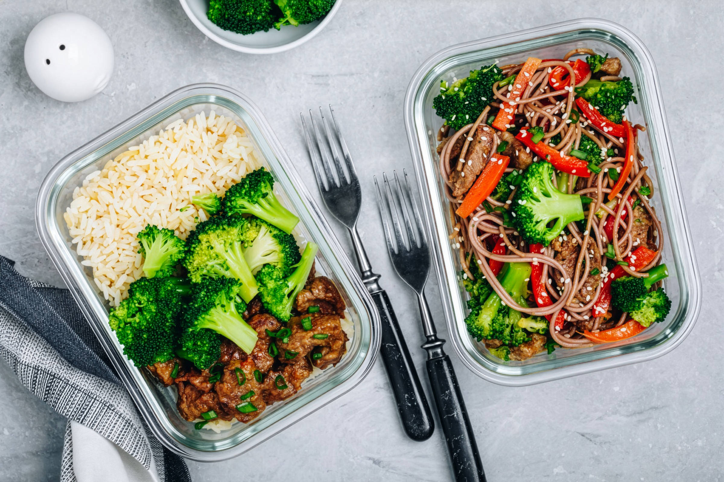 Zubereitetes Essen mit Reis, Gemüse und Vollkornudeln in zwei Glasschalen.