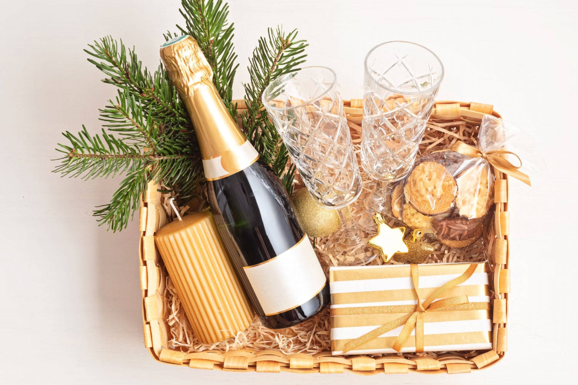 Geschenkkorb im Gold-Look mit Sekt, Gläsern, Leckereien und Dekoration.