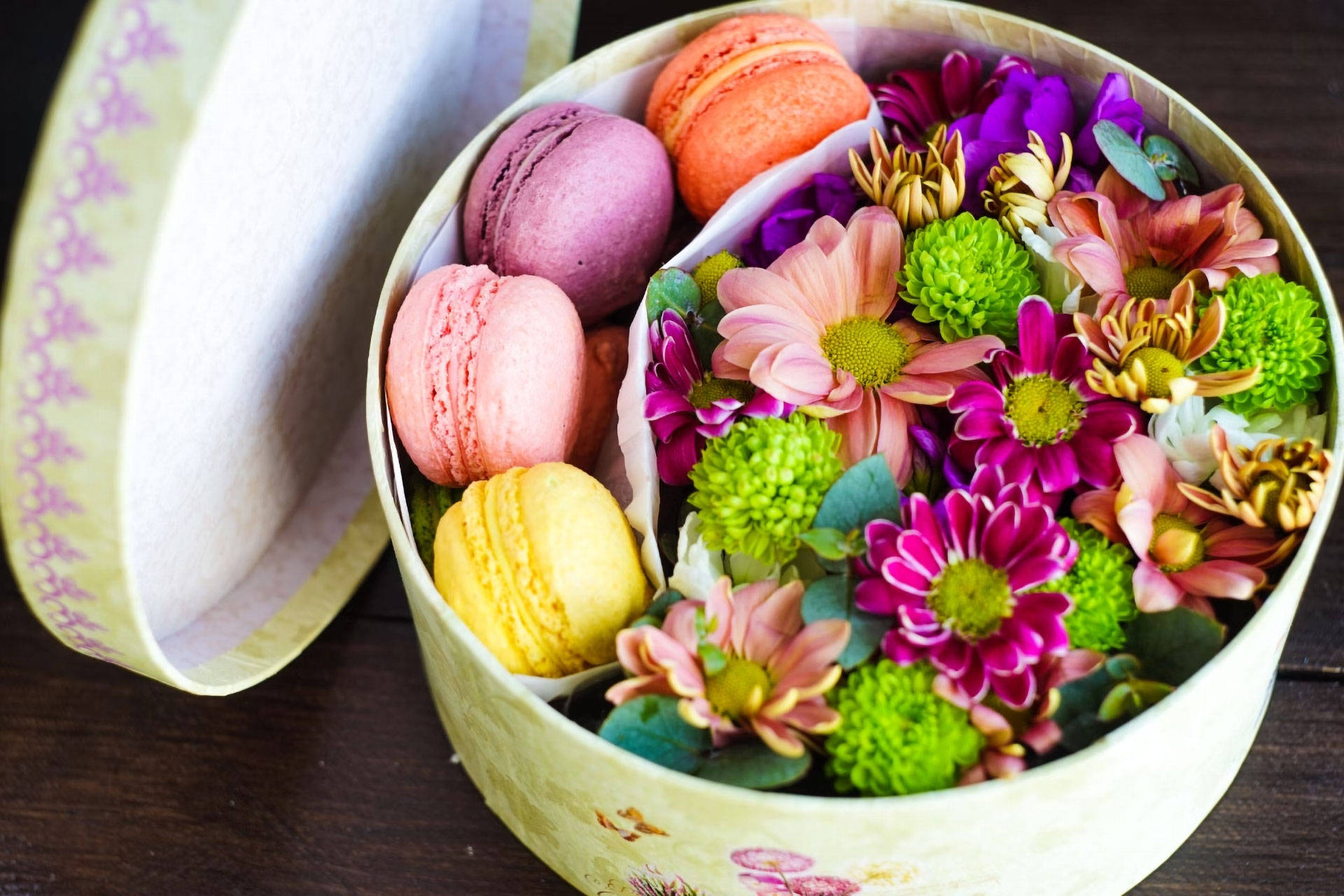Eine Geschenkbox, gefüllt mit Blumen und bunten Macarons.