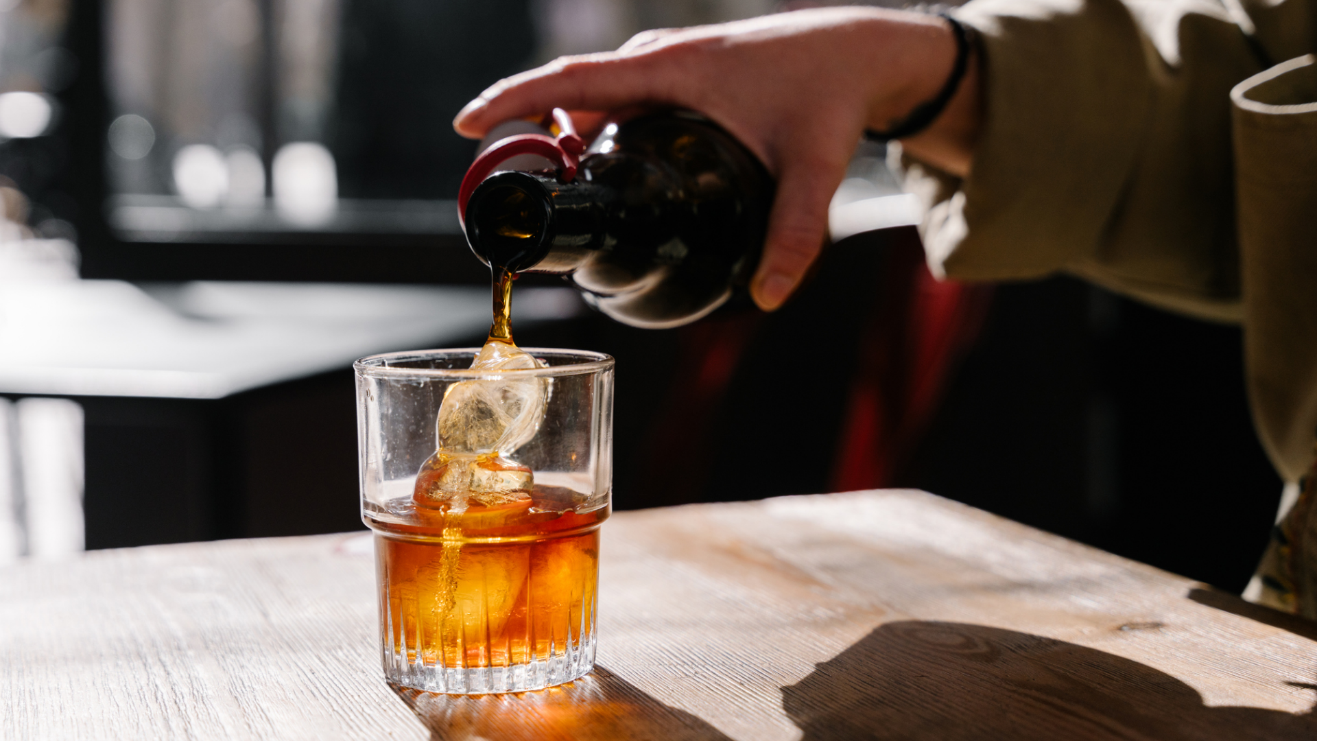 Getränk wird in ein Glas mit Eis gegossen.