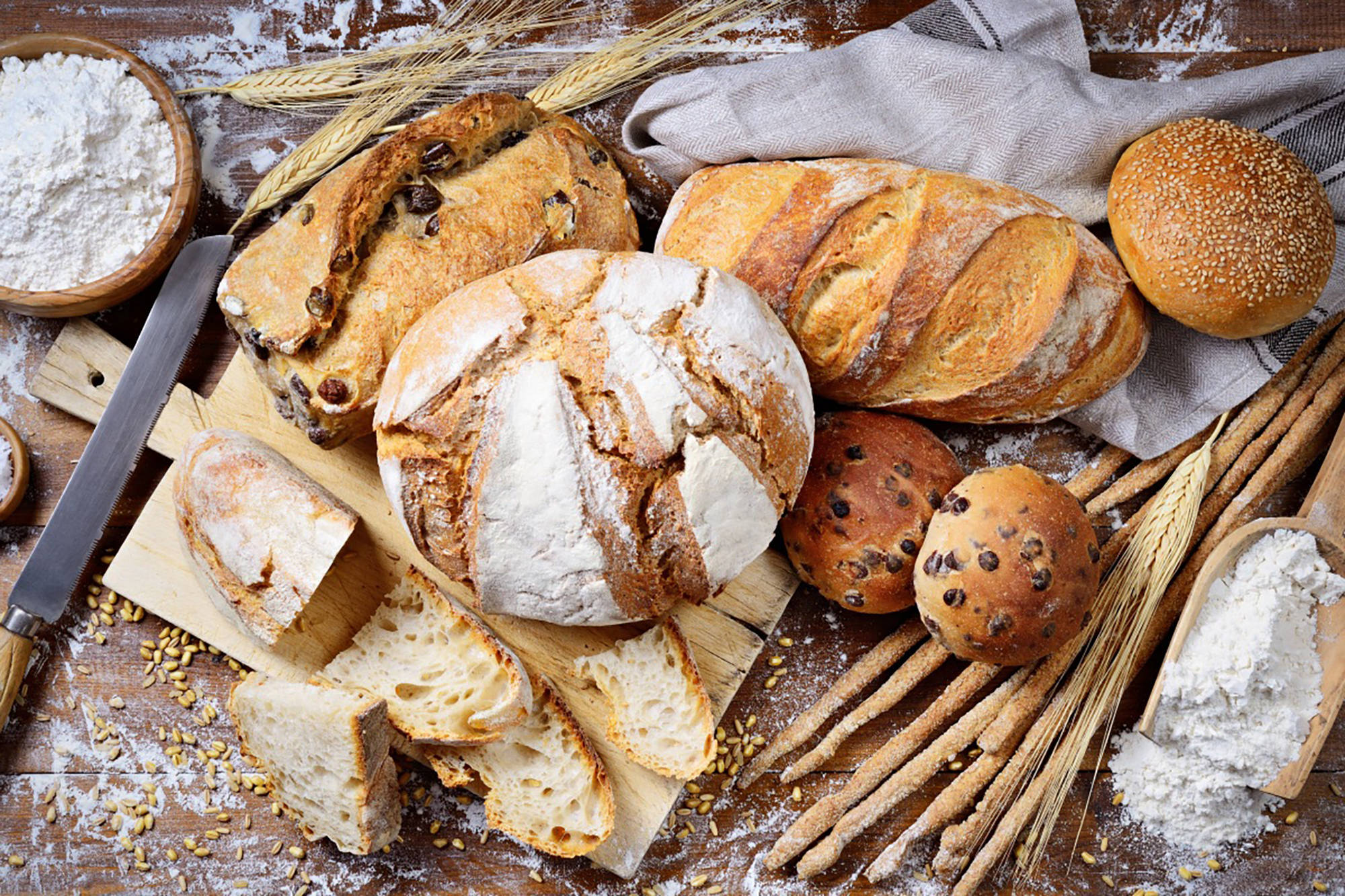 Knusprig gebackene glutenfreie Brote und Brötchen auf einem Holzbrett.