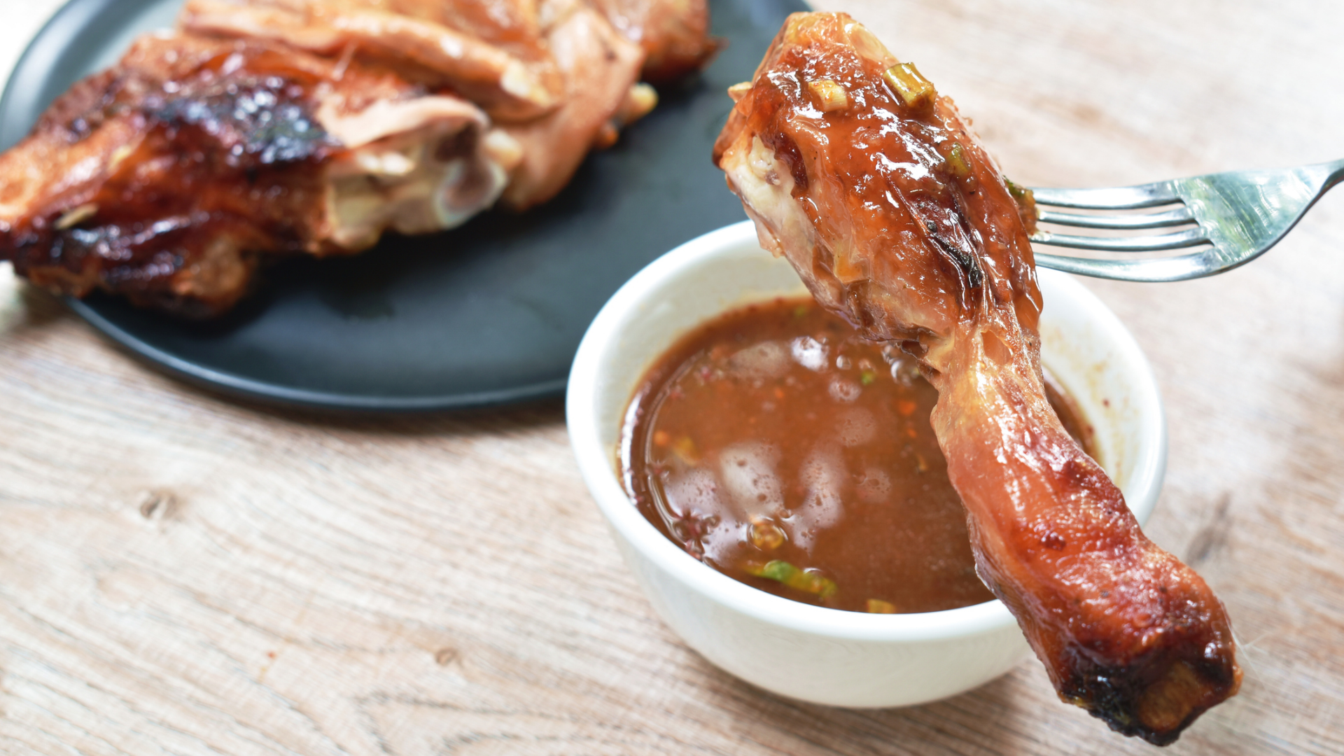 Gegrilltes Hähnchenbein wird in Sauce getunkt.