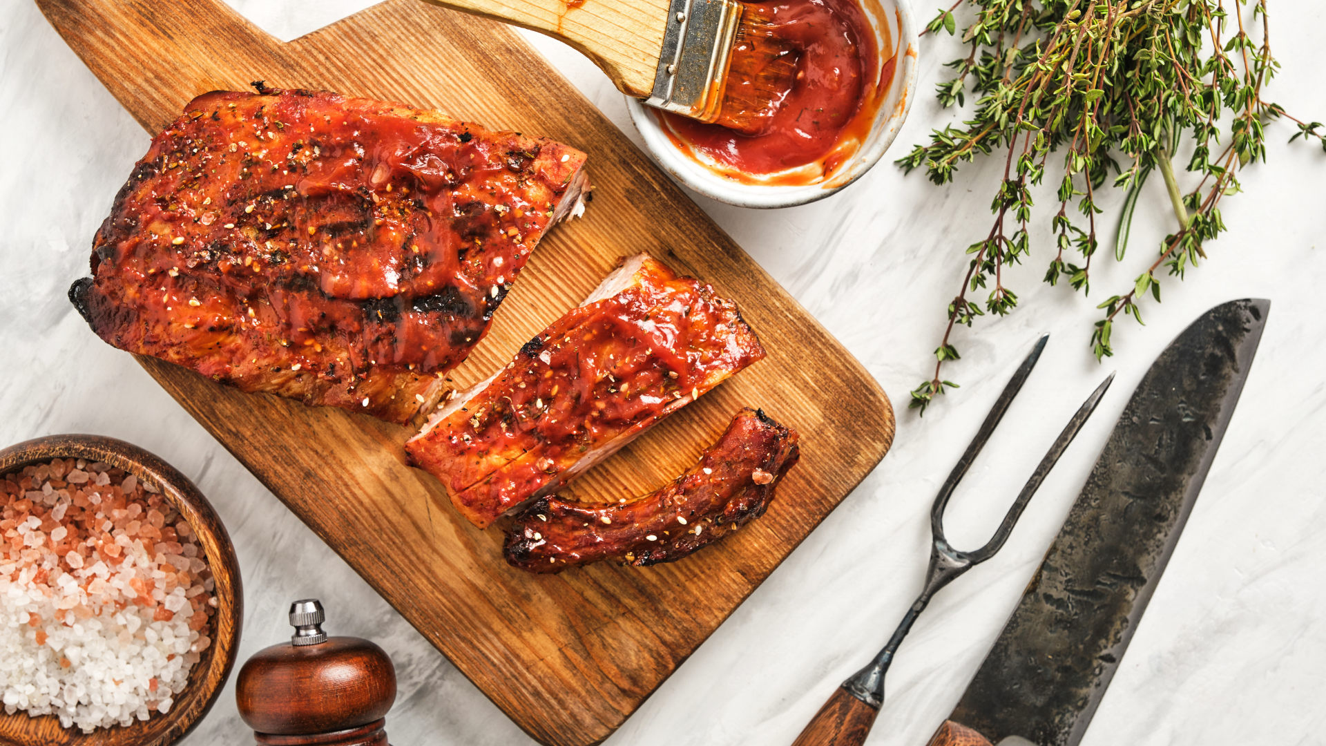 Spareribs mit Grillsauce auf Holzbrett, Thymian, Salz.