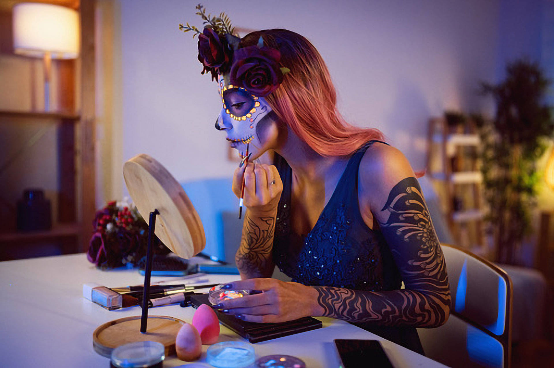 Eine Frau schminkt sich an einem Tisch für den Día de los Muertos.