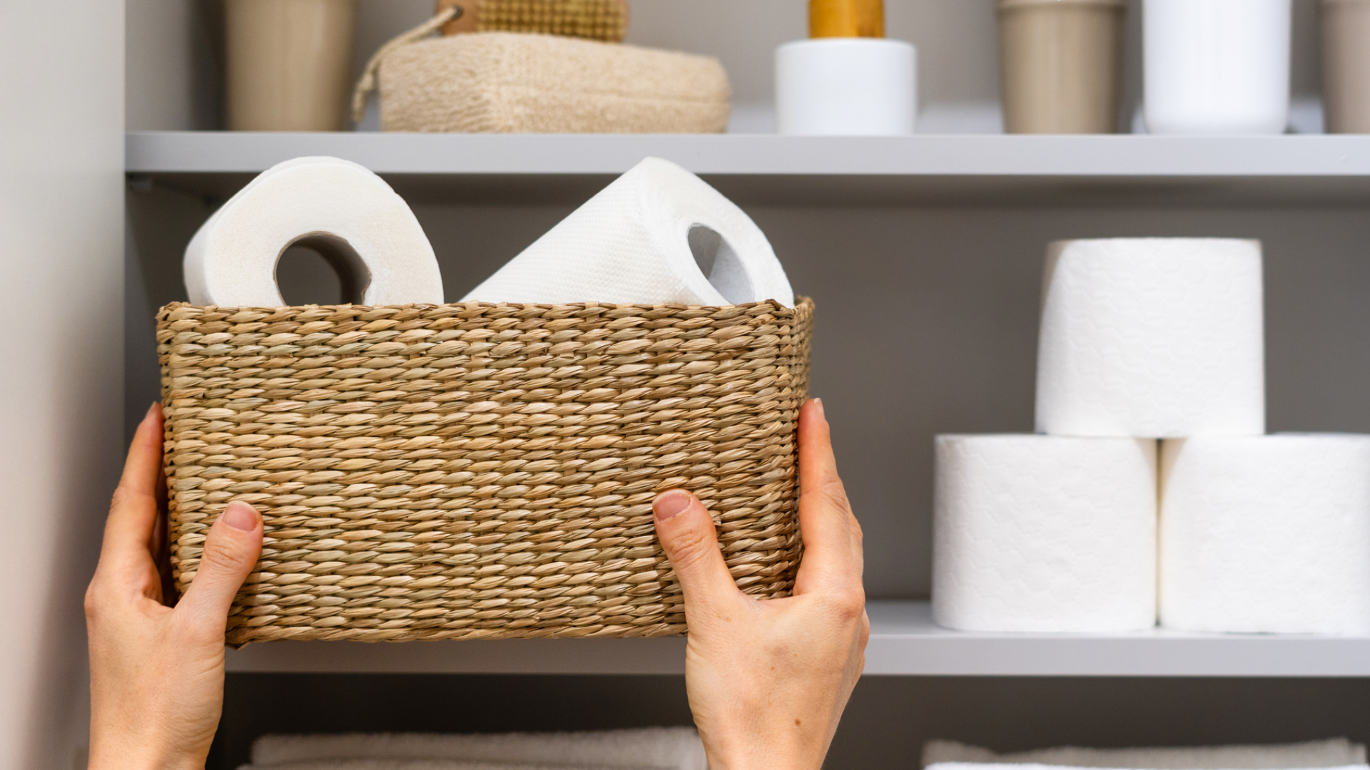 Hände halten Korb mit Toilettenpapier vor Regalen.