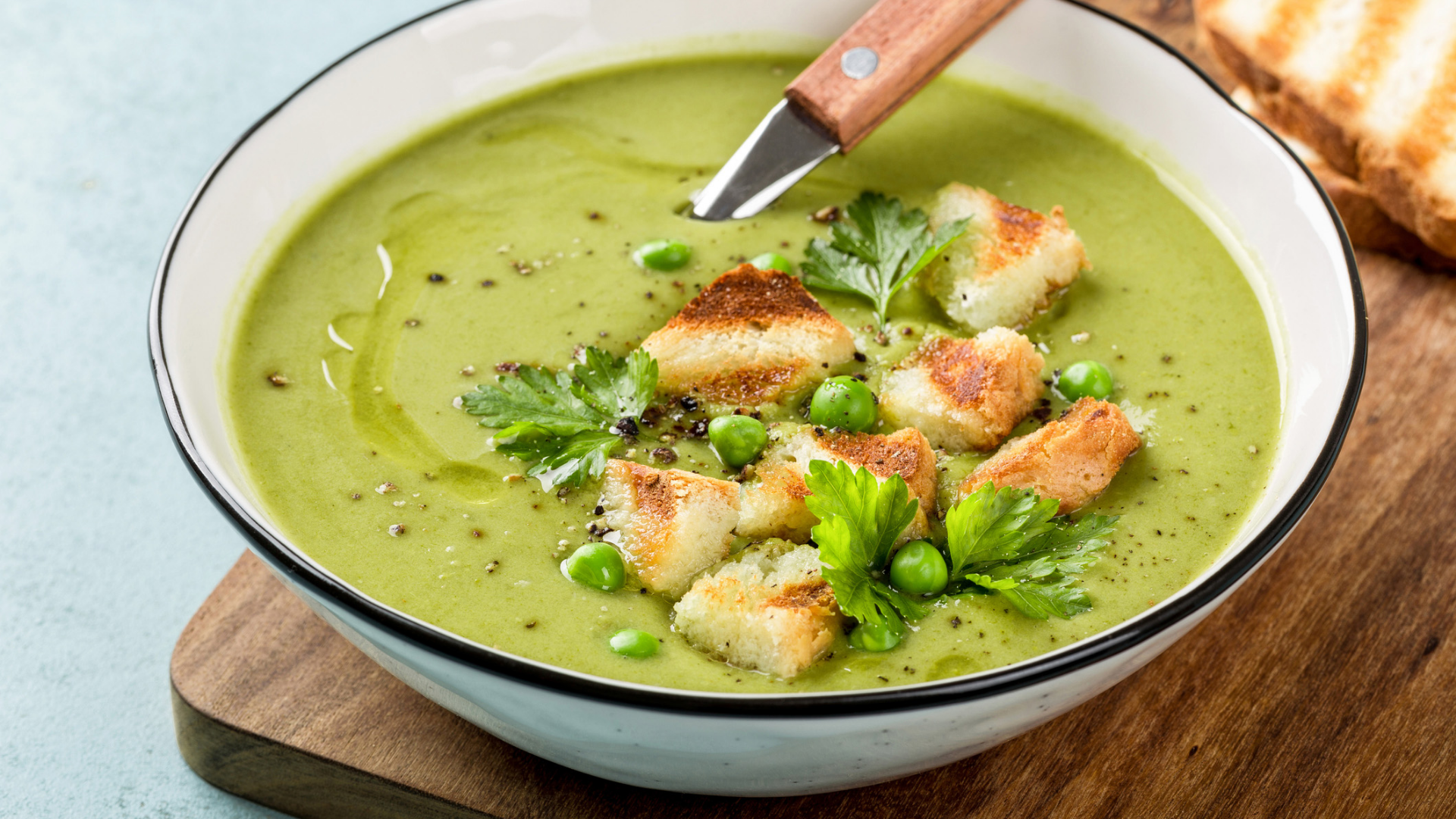 Grüne Erbsensuppe mit Croutons, Erbsen und Petersilie.