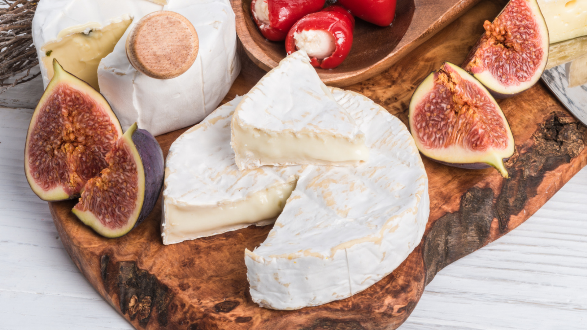 Käsesorten und Feigen auf Holzbrett arrangiert.