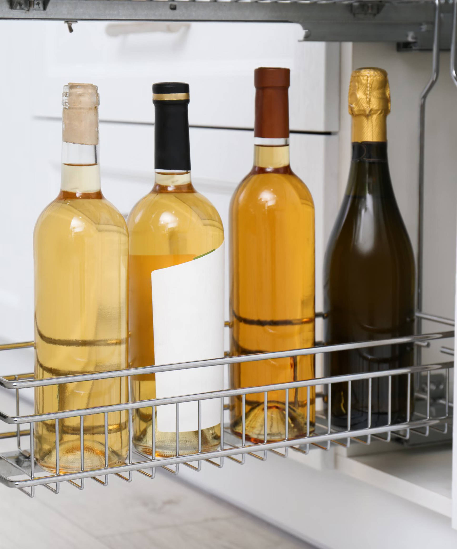 Vier Weinflaschen stehen in einem ausziehbaren Küchenregal.