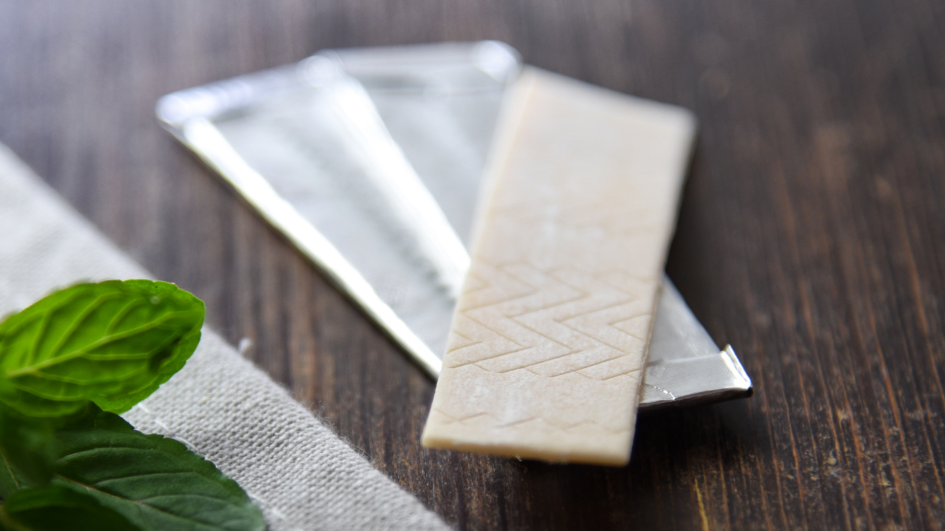 Kaugummi, Verpackung und Minze auf Holztisch.