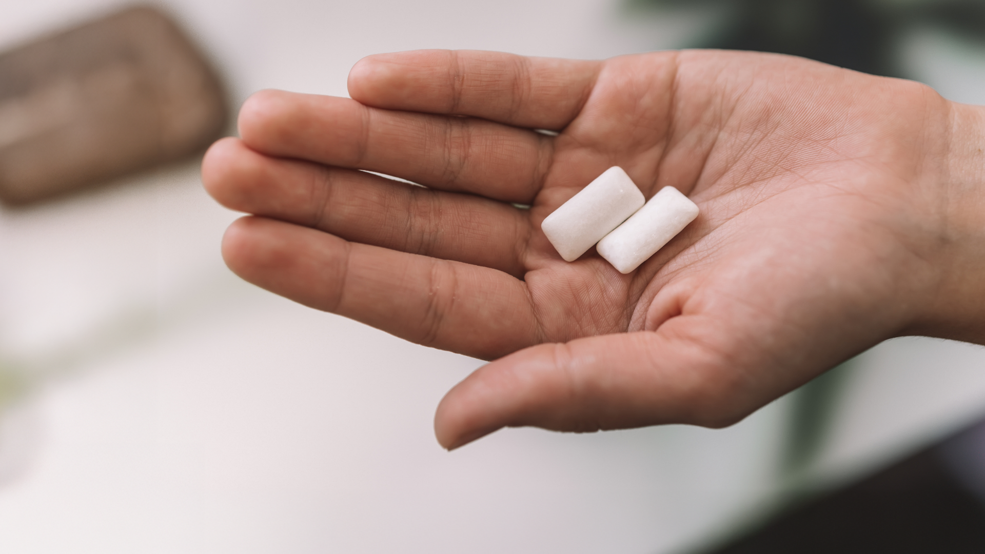 Zwei Kaugummistreifen in offener Handfläche, Nahaufnahme.