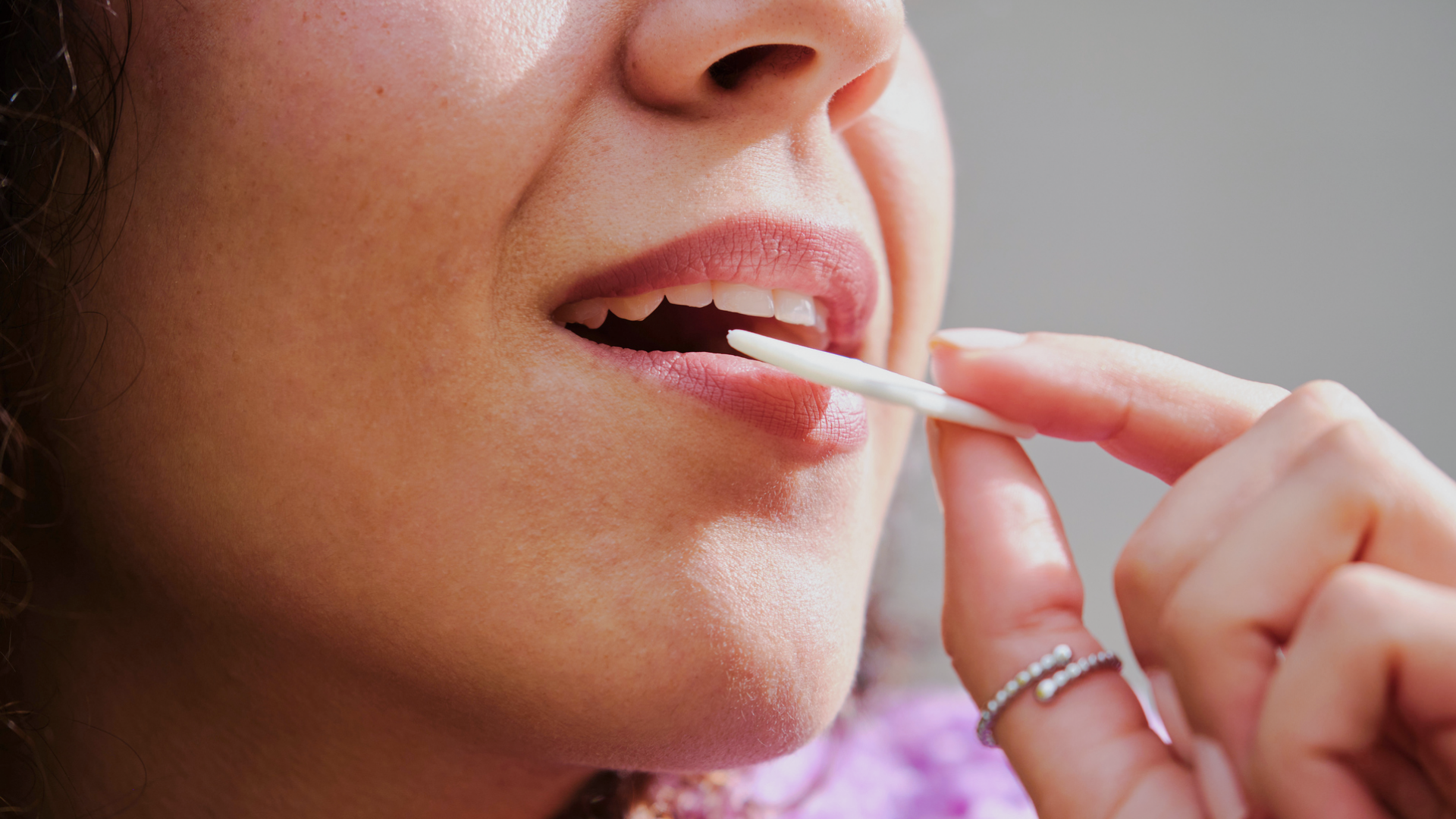 Frau steckt Kaugummistreifen in den Mund.
