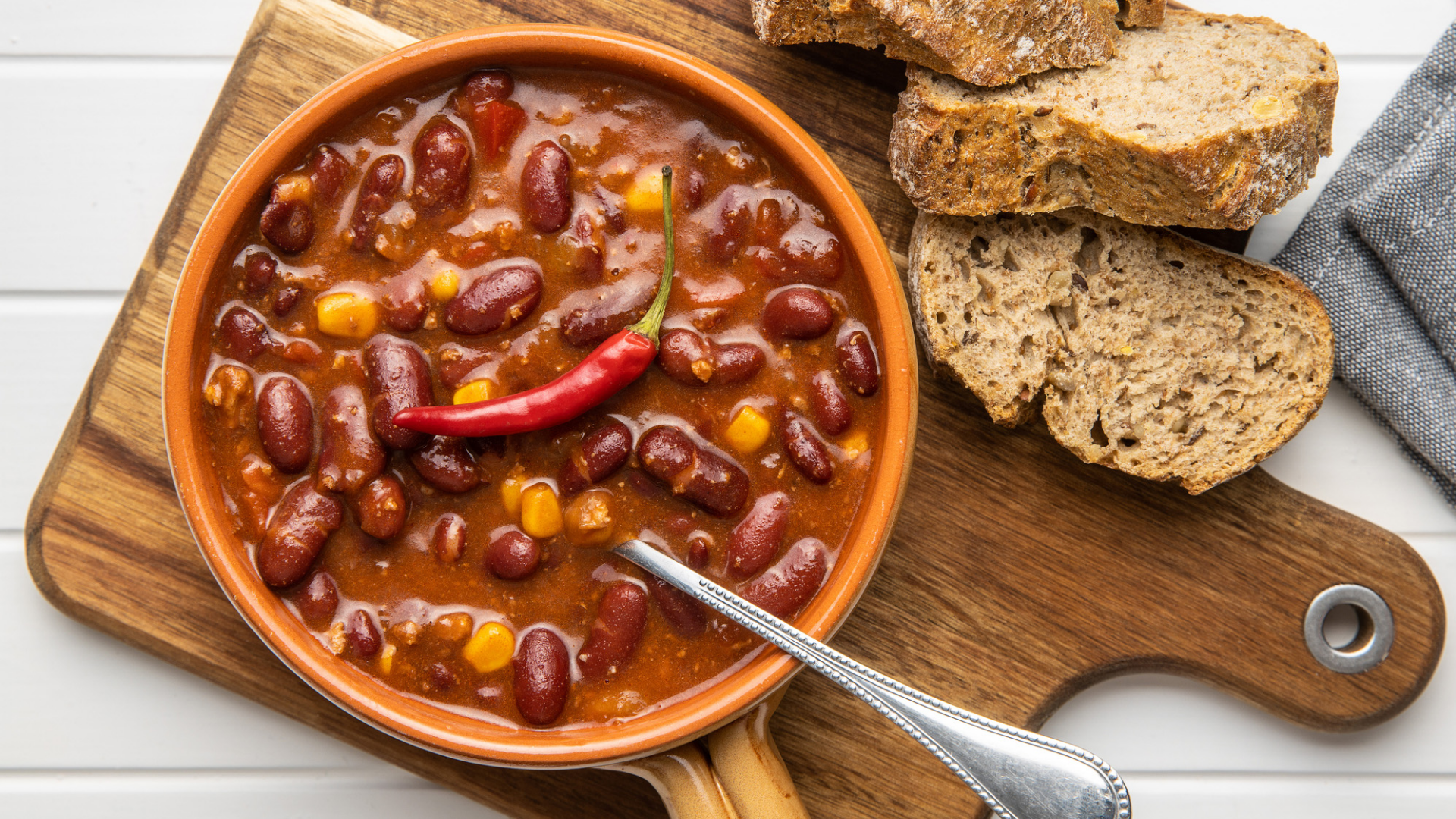 Chili, Brot und Chilischote auf Holzbrett.