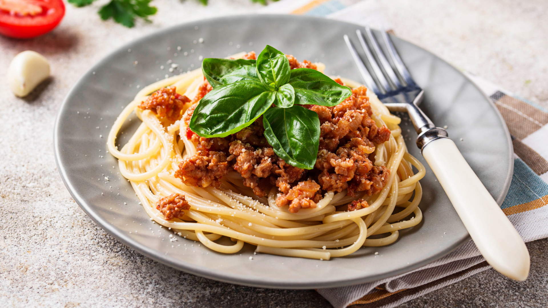 Spaghetti Bolognese auf einem Teller mit Basilikum und Gabel.
