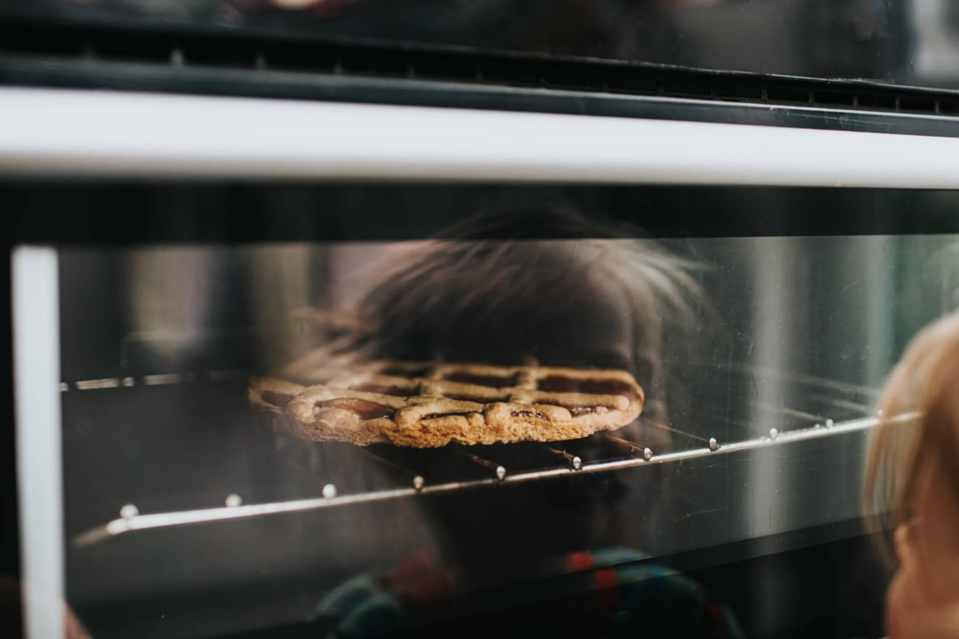 Backender Gitterkuchen im Ofen, Reflexion eines Kindes.