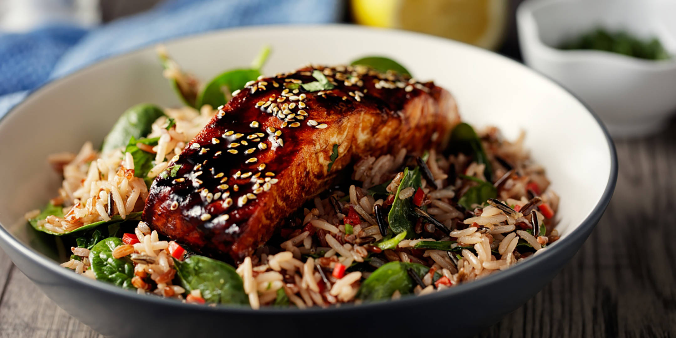 Glasierter Lachs mit Sesam auf Reis und Spinat.