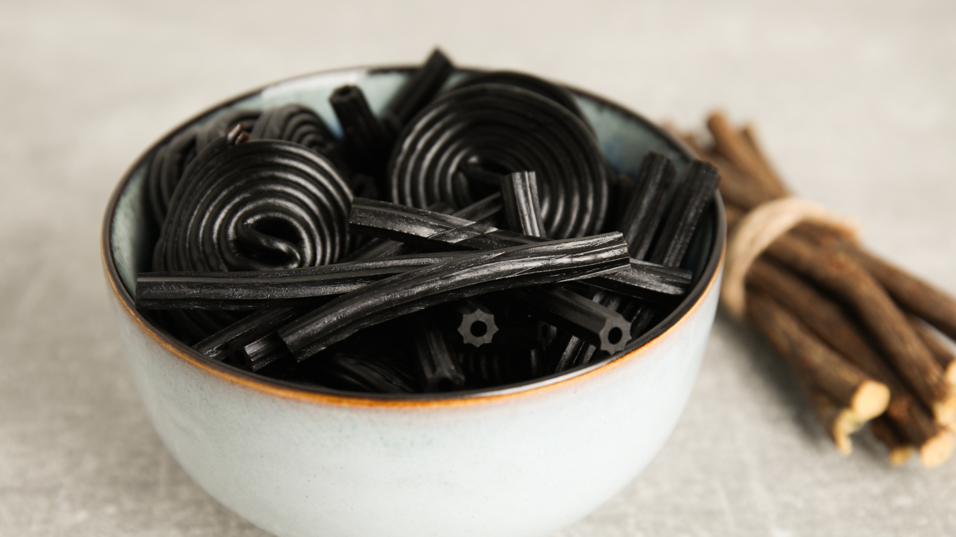 Schale mit Lakritzschnecken und -stangen, Lakritzstangen im Hintergrund.