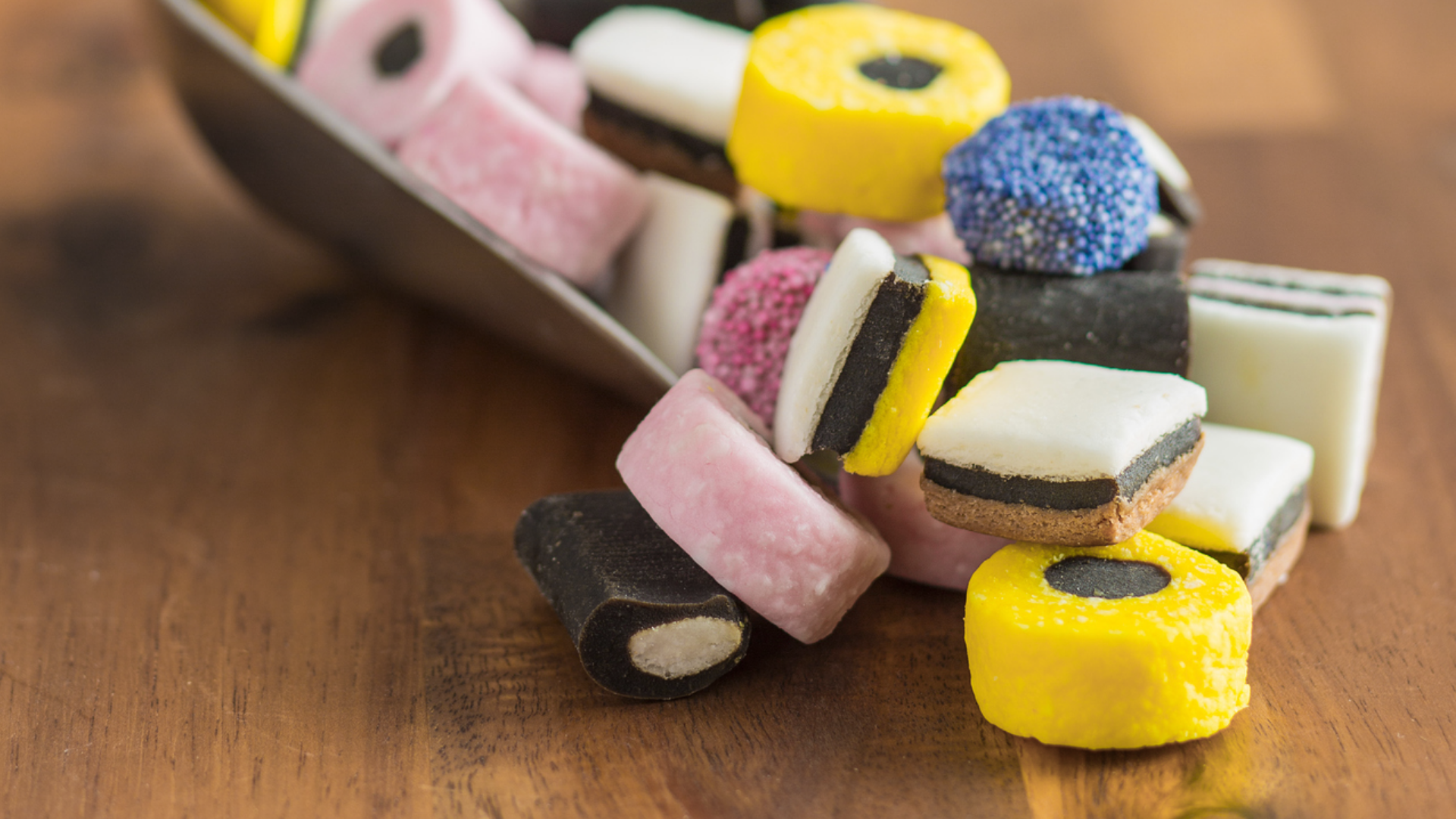 Verschiedene Lakritzsorten in einer Schale auf einem Holztisch.