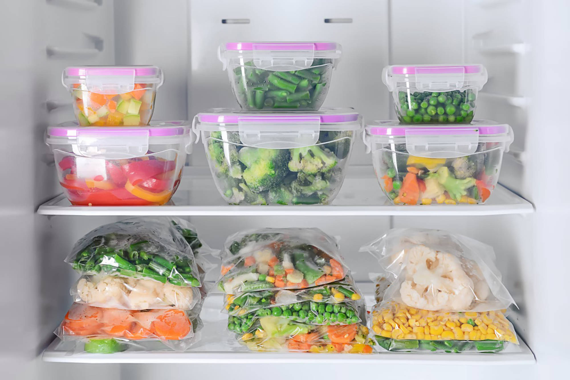 Gefrierfach mit  gemischtem, gefrorenem Gemüse wie Paprika, Brokkoli und Mais in Gefrierbeuteln und Plastikdosen verpack