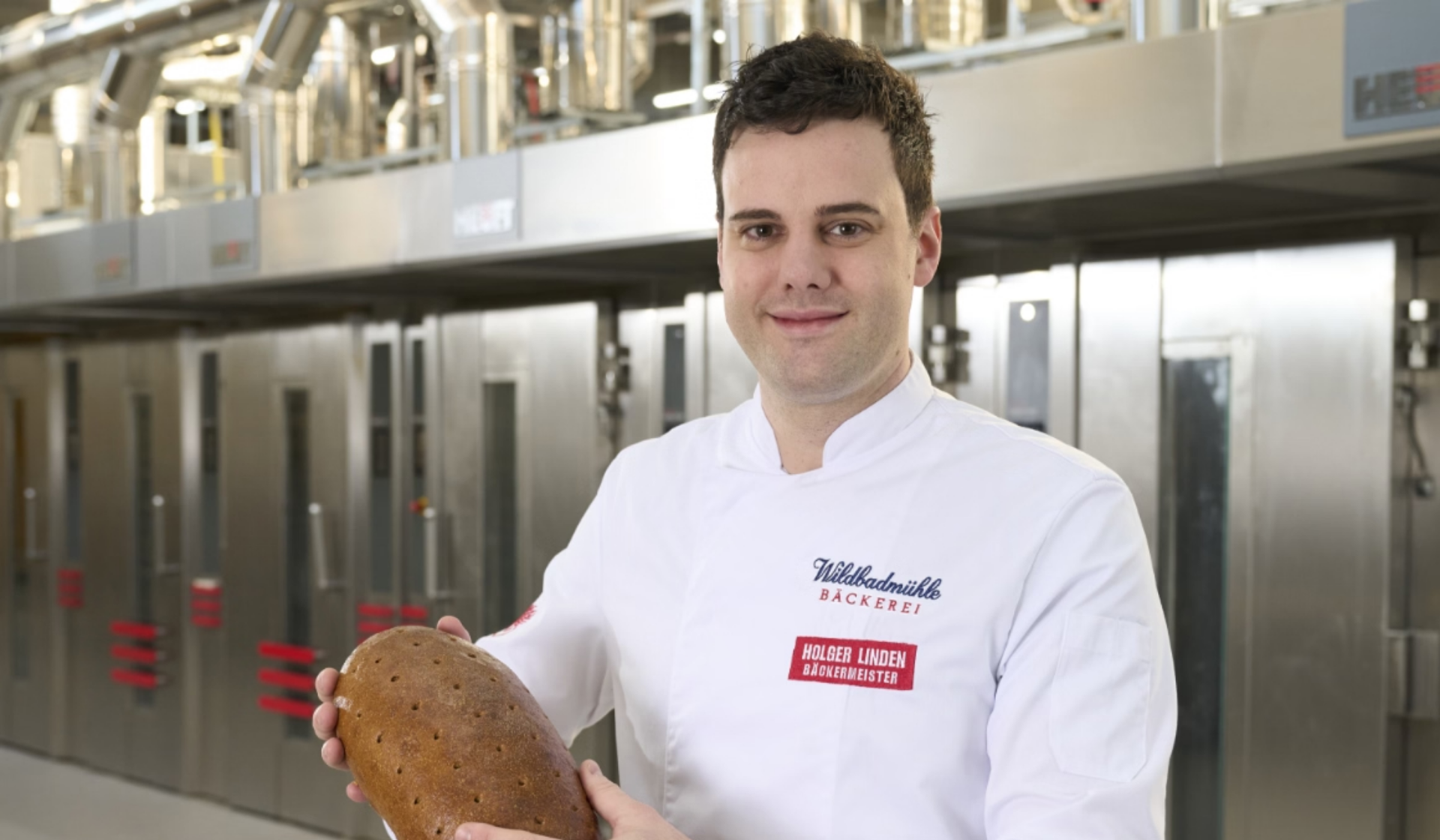 Bäckermeister Holger Linden hält Brot in einer Bäckerei.