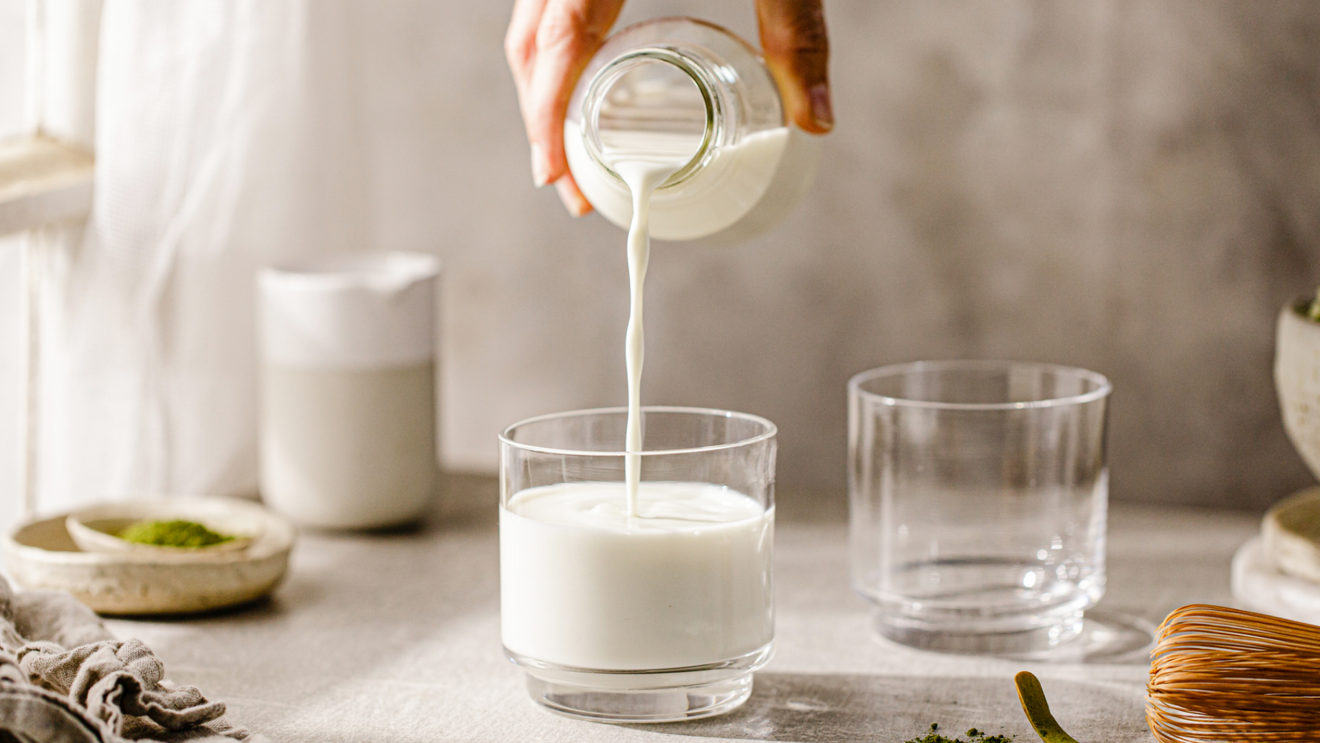 Milch wird aus Flasche in Glas gegossen.