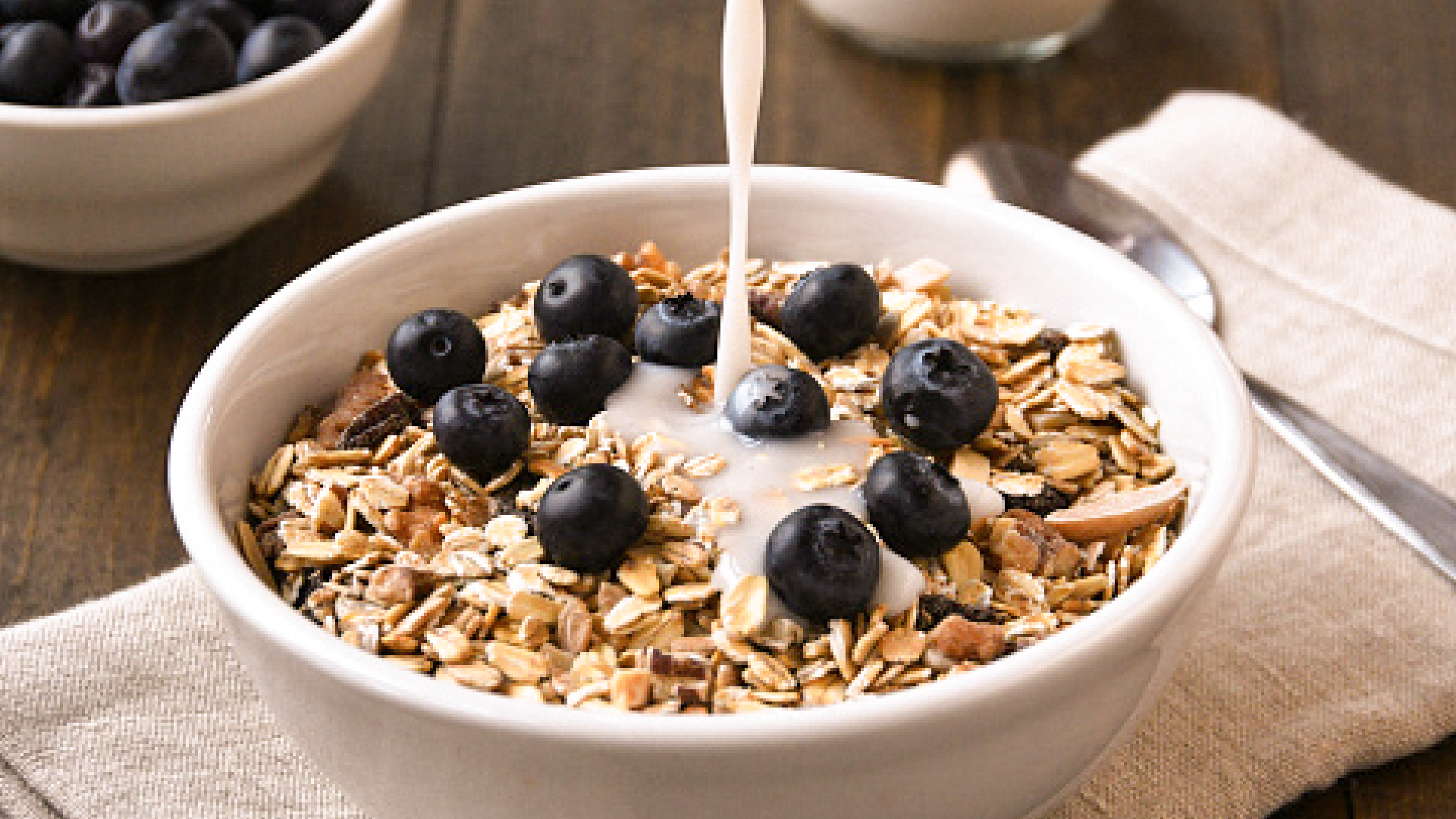 Müsli mit Heidelbeeren, Milch wird eingegossen.