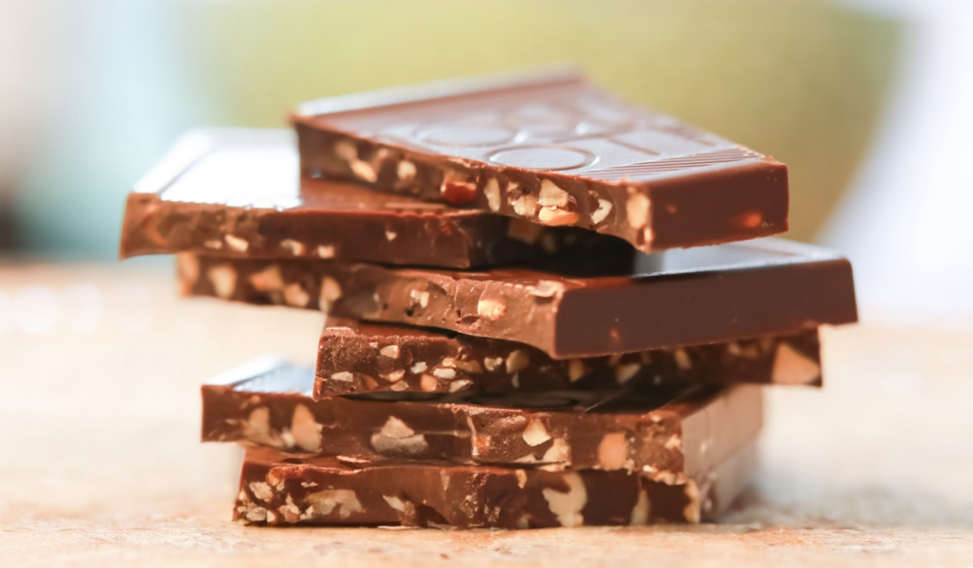 Stapel dunkler Schokoladenstücke mit Nüssen.