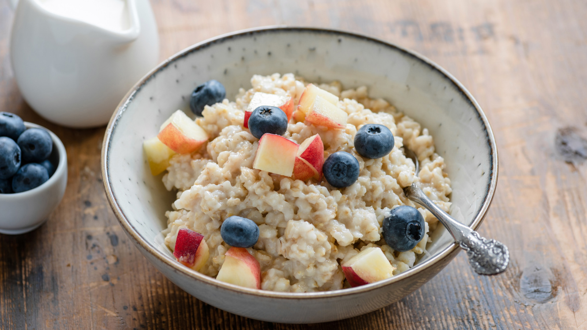 Schüssel Haferbrei mit Beeren und Apfelstücken.