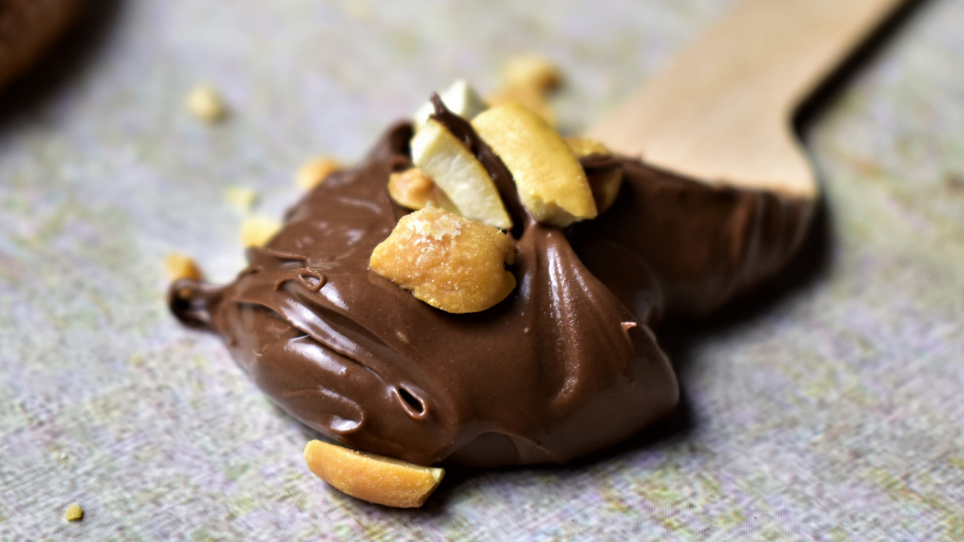 Nuss-Nugat-Creme mit Nüssen und Holzlöffel.