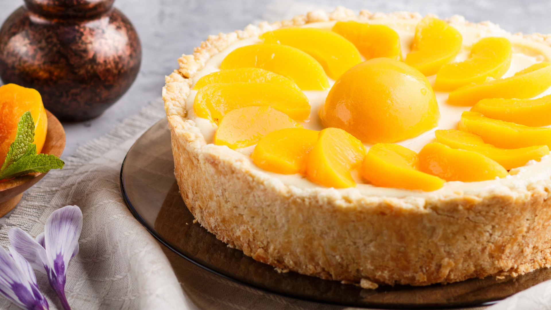 Pfirsichkuchen mit Teigboden und Creme-Füllung auf dem Tisch.