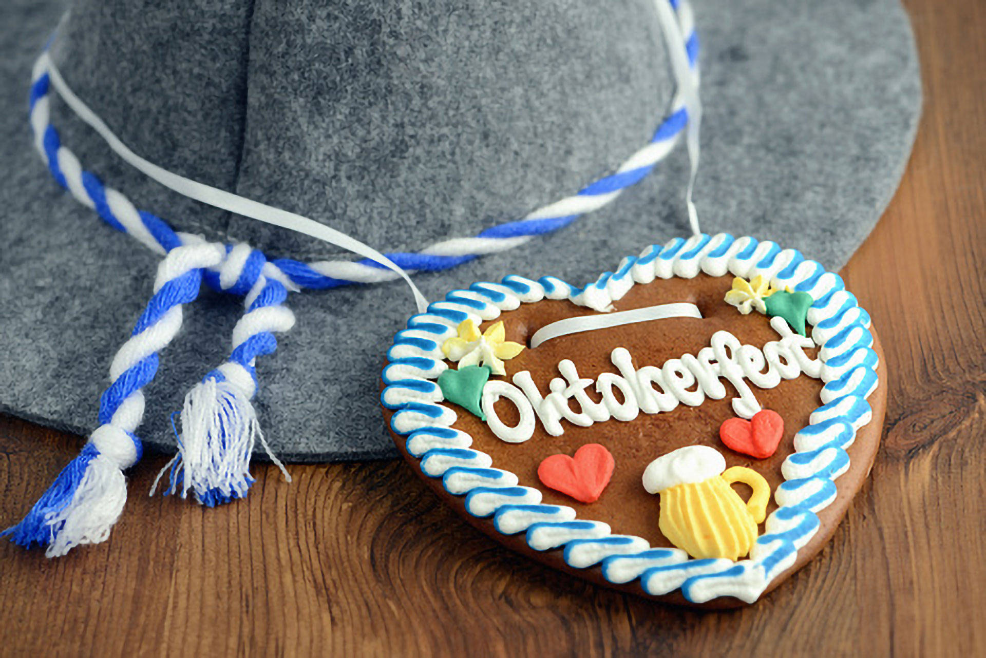 Auf einem Holztisch liegen ein Oktoberfest‑Lebkuchenherz und ein traditioneller Oktoberfest‑Hut.