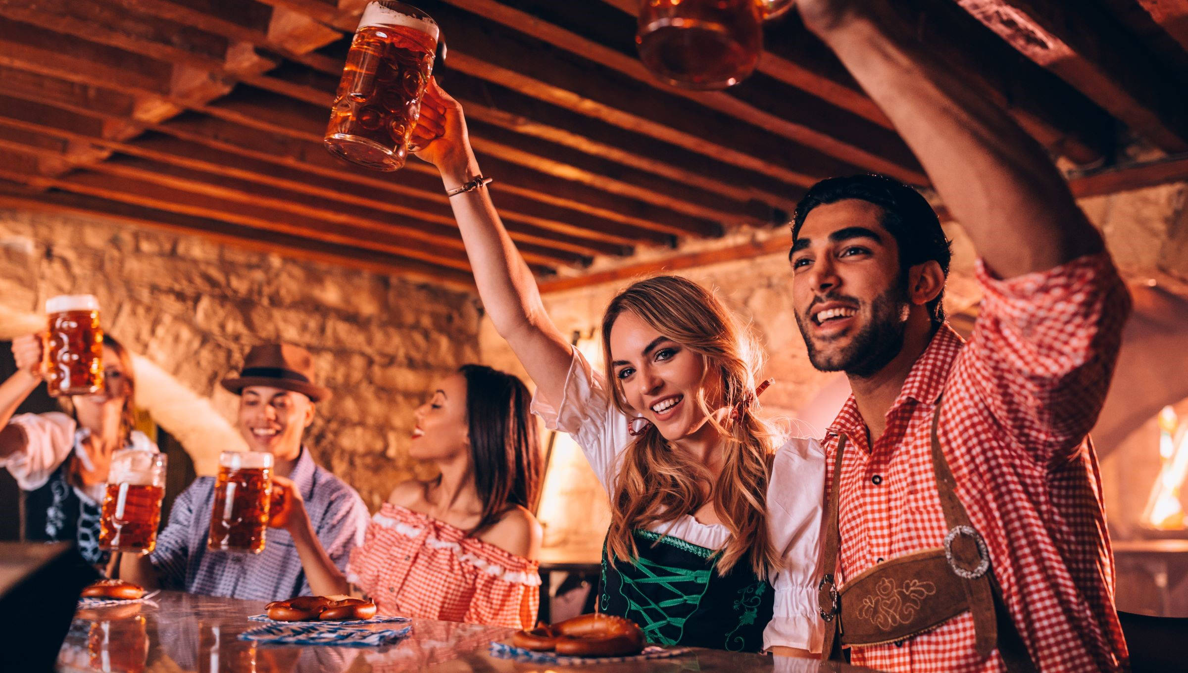 Eine Gruppe in traditioneller Tracht feiert in einem bayerischen Lokal mit Bierkrügen in den Händen.